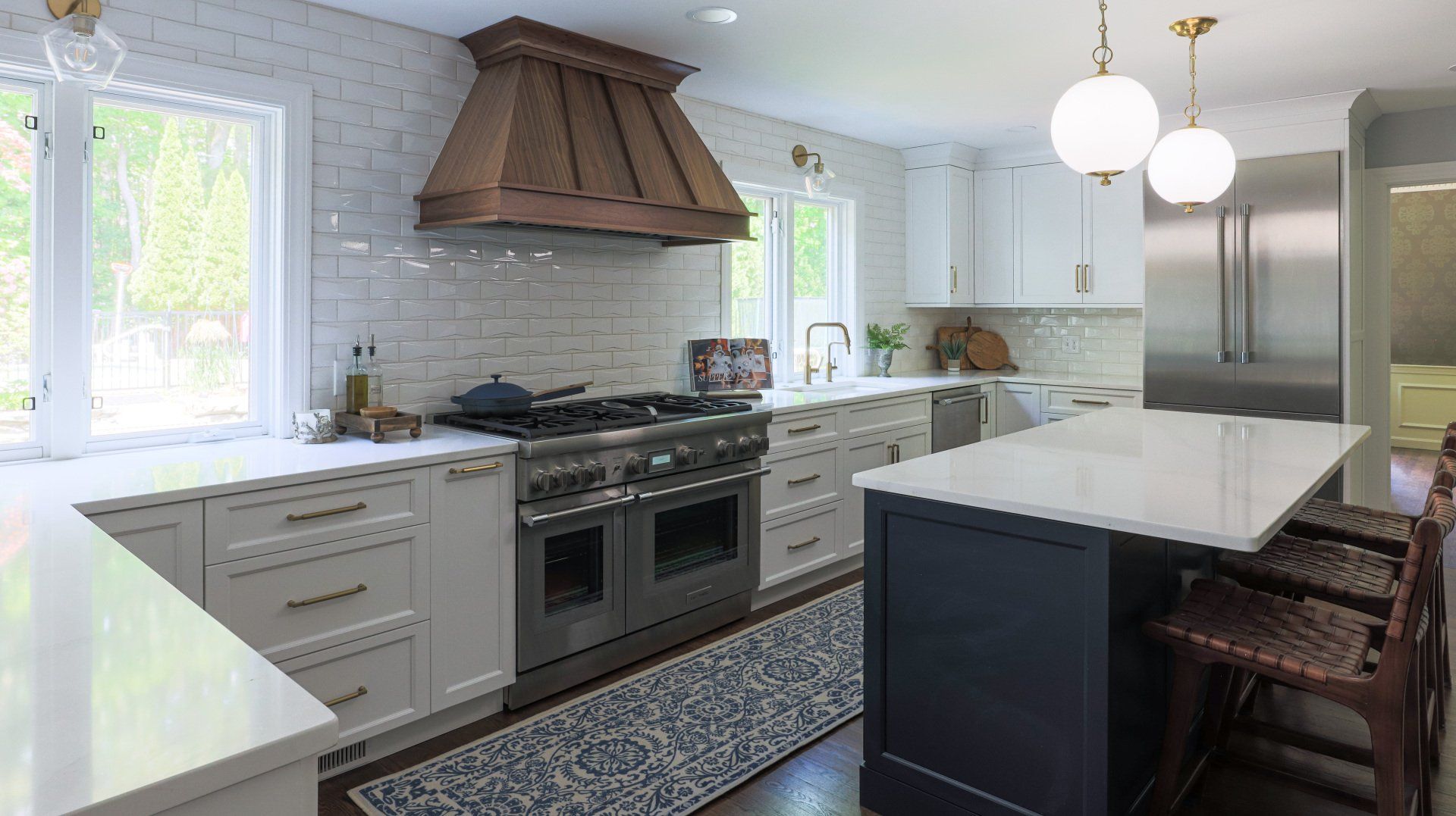Bright modern kitchen with white cabinets, large island, stainless appliances, and copper range hood