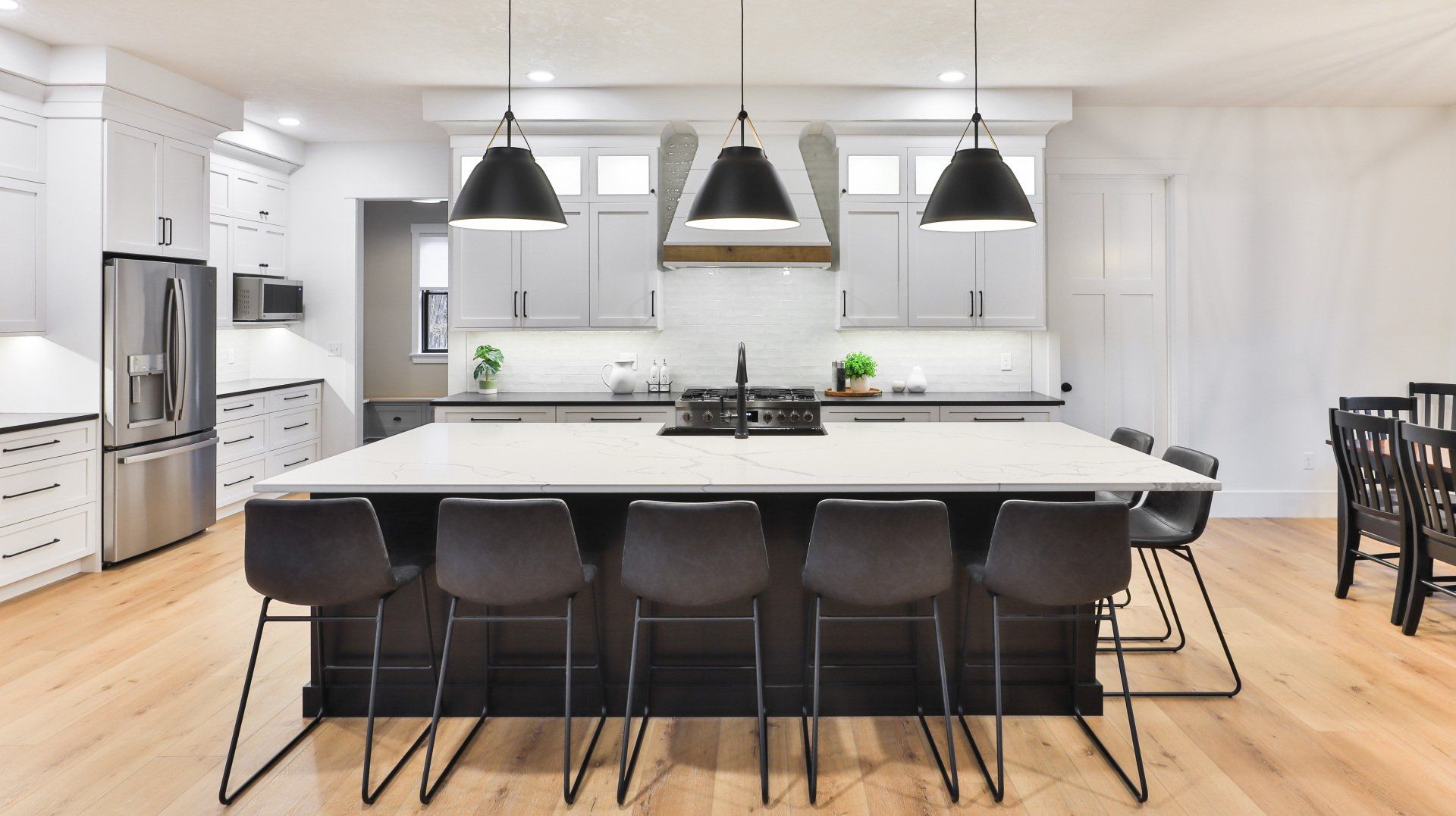 Modern white kitchen with black island, pendant lights, and barstools