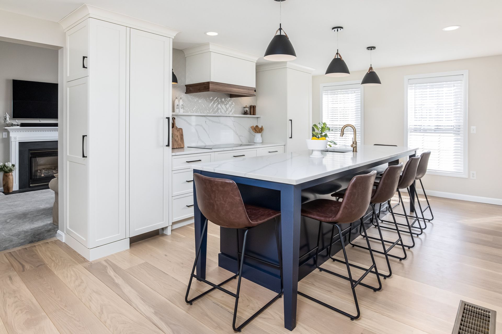 Bright modern kitchen with a white island, black pendant lights, and brown bar stools
