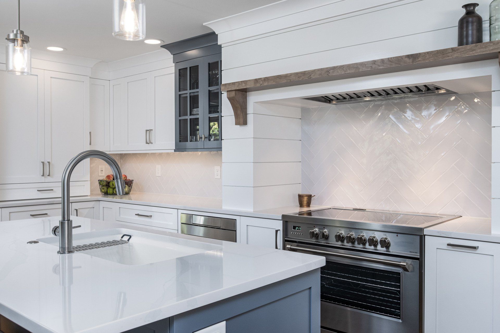 Modern white kitchen with island, stainless steel range, and marble backsplash