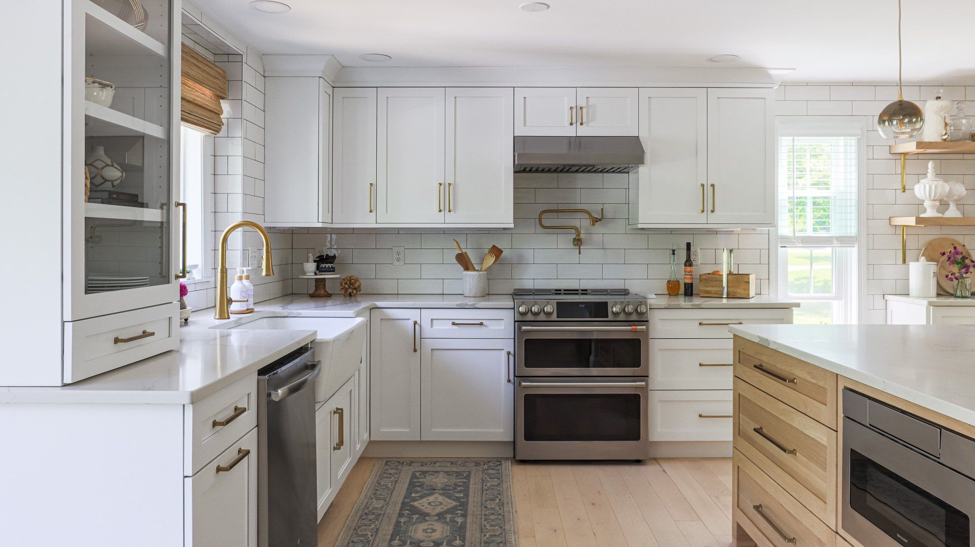 Bright white modern kitchen with island, stainless steel appliances, and patterned runner rug