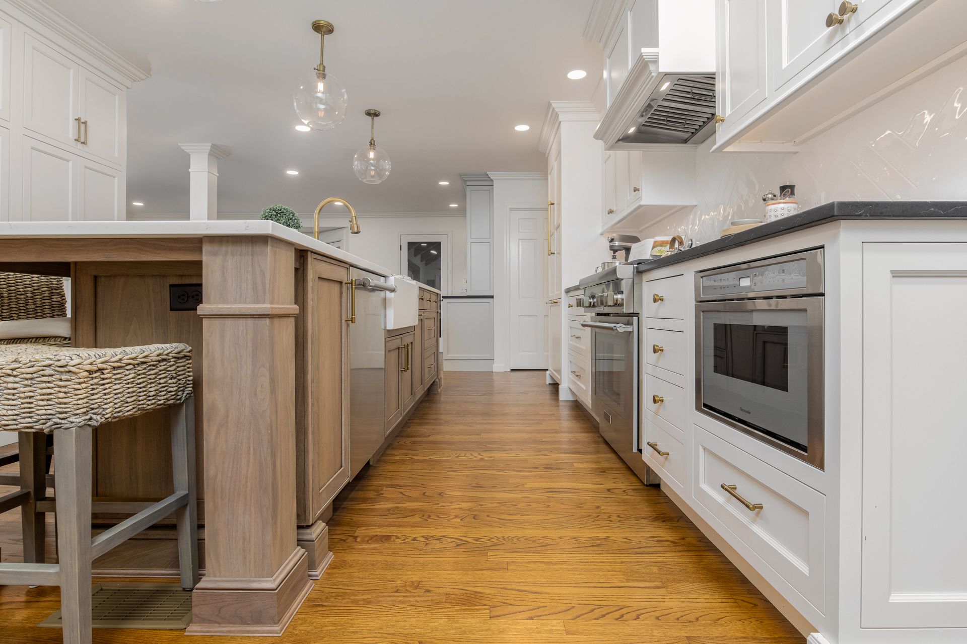 Bright white kitchen with wood floors, island seating, and stainless steel appliances.