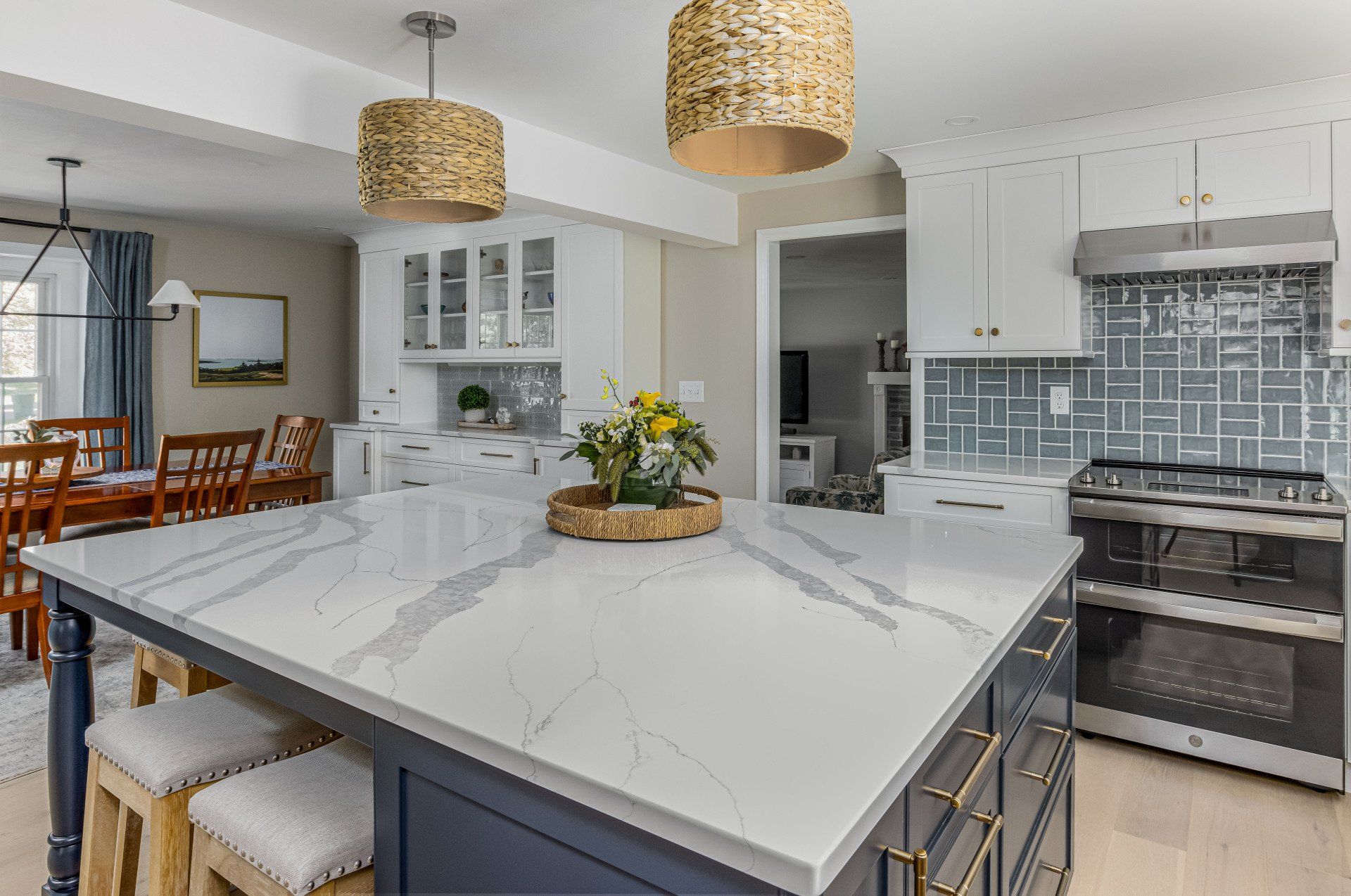 Modern white kitchen with marble island, woven pendant lights, and stainless steel appliances