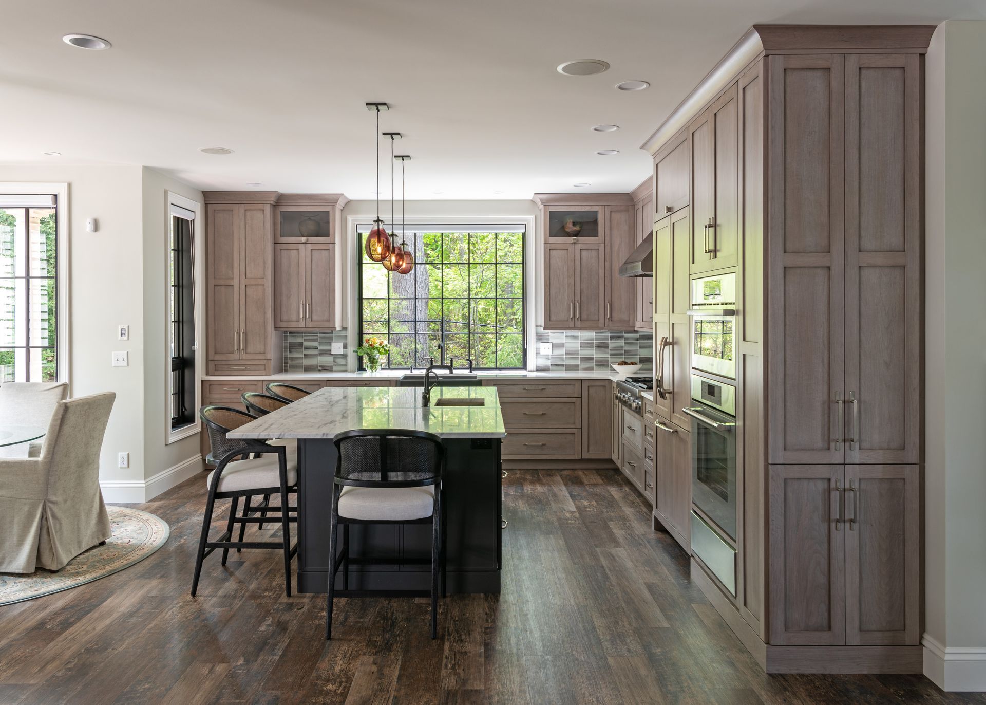 Modern kitchen with large island, gray cabinets, white countertops, and wood floors, seen from the dining area