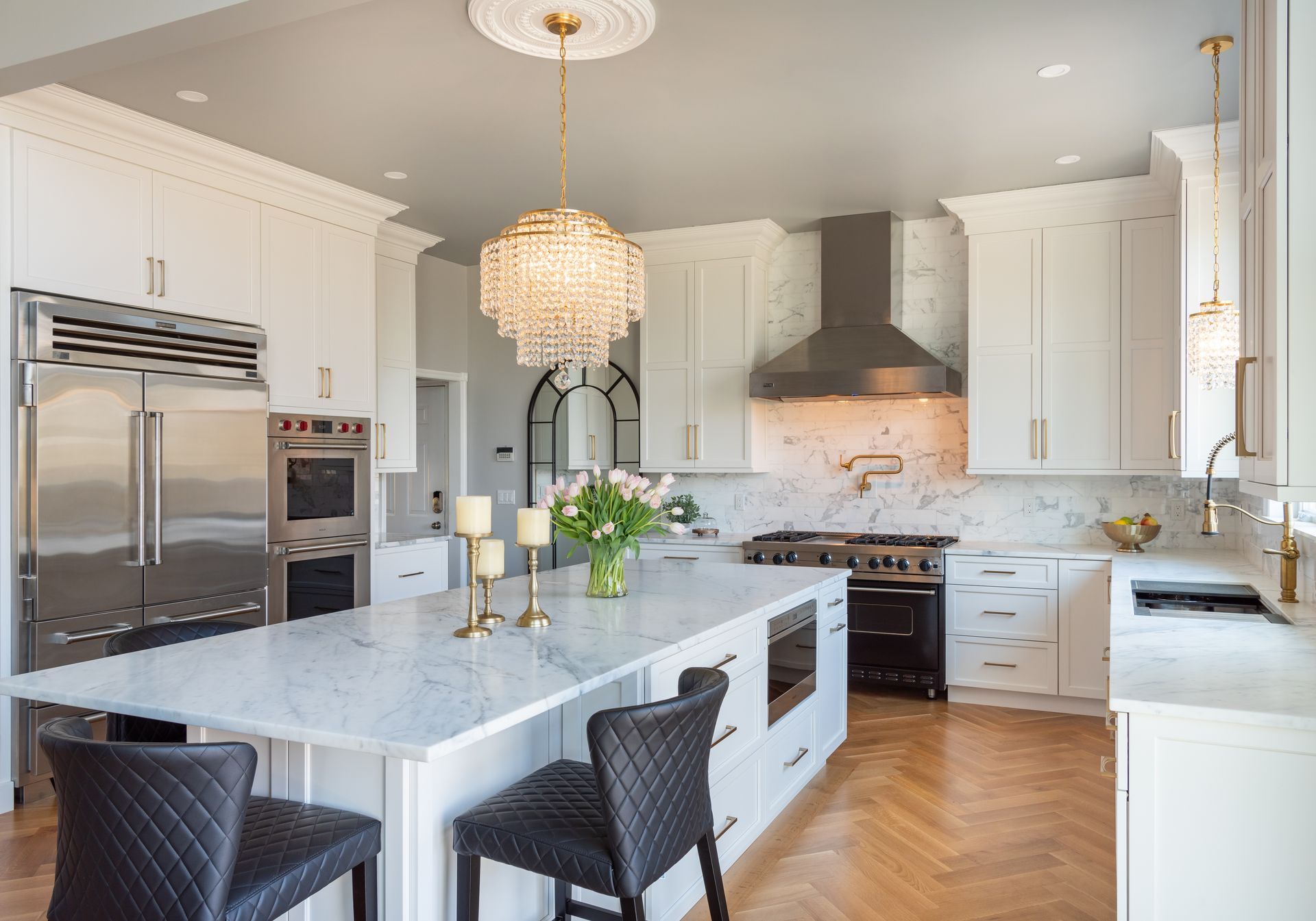 Bright modern kitchen with marble island, white cabinets, stainless appliances, and pendant lights
