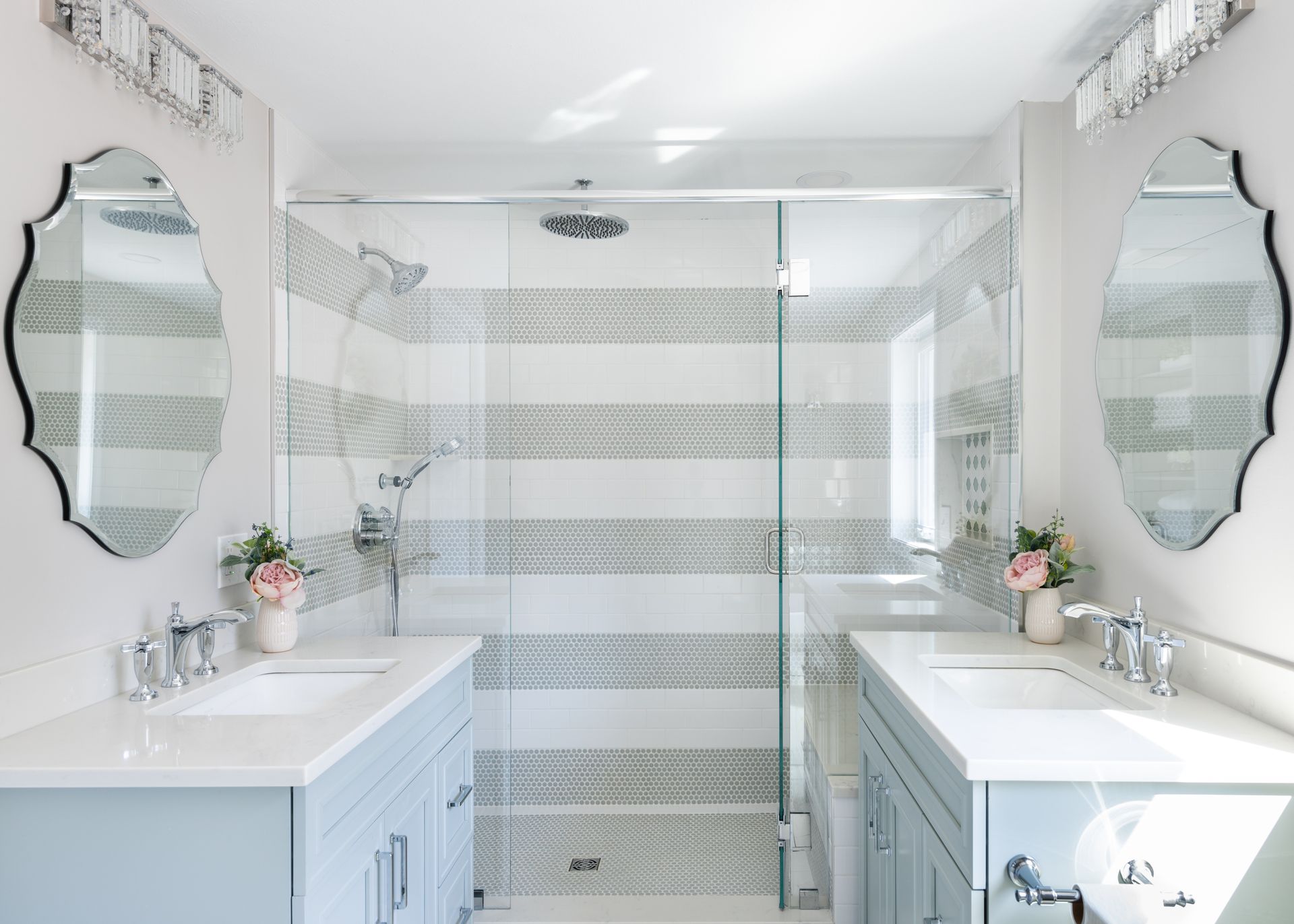 Bright white bathroom with twin vanities, mirrors, and a striped glass shower wall
