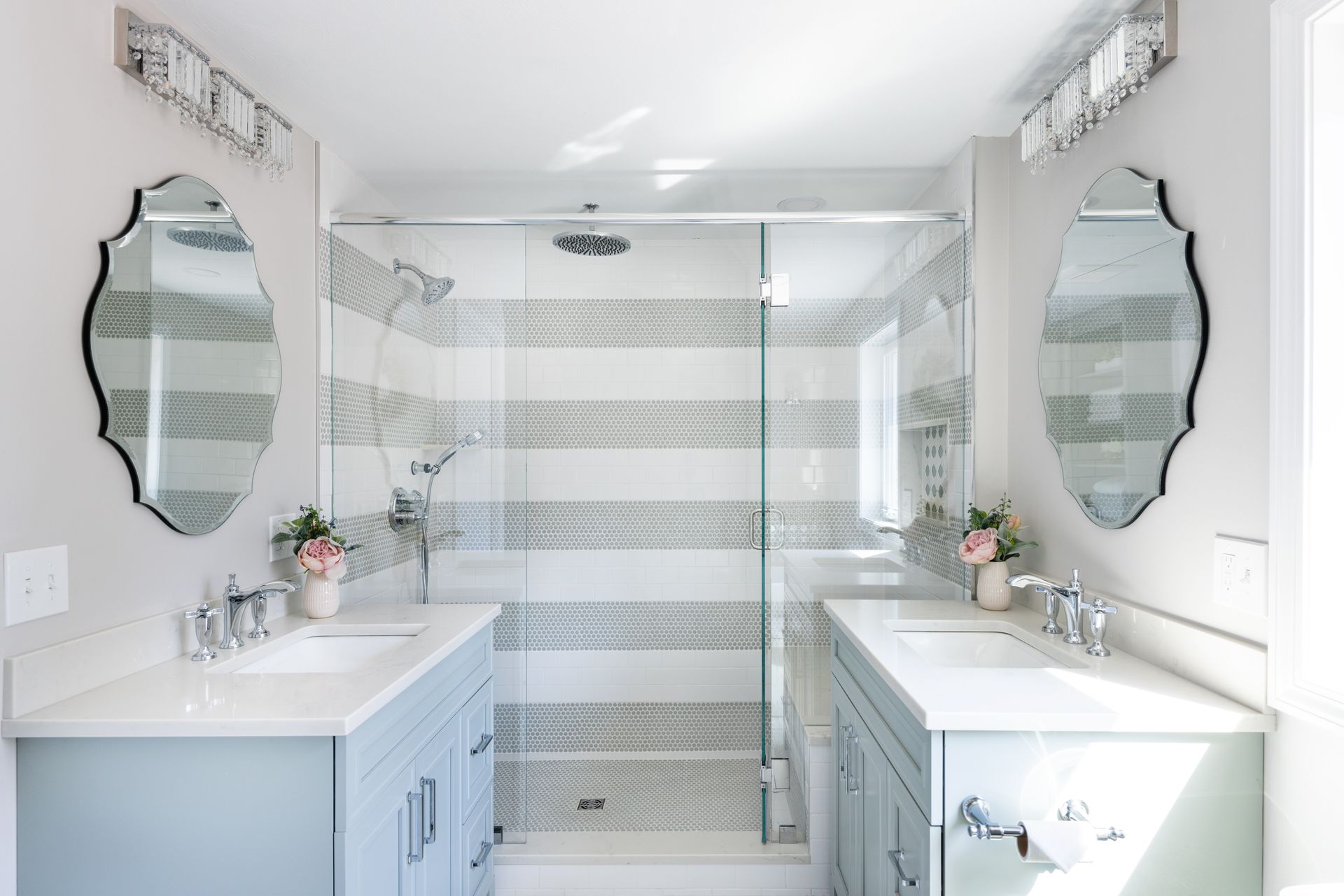Bright white double vanity bathroom with mirrors, sinks, and glass shower enclosure