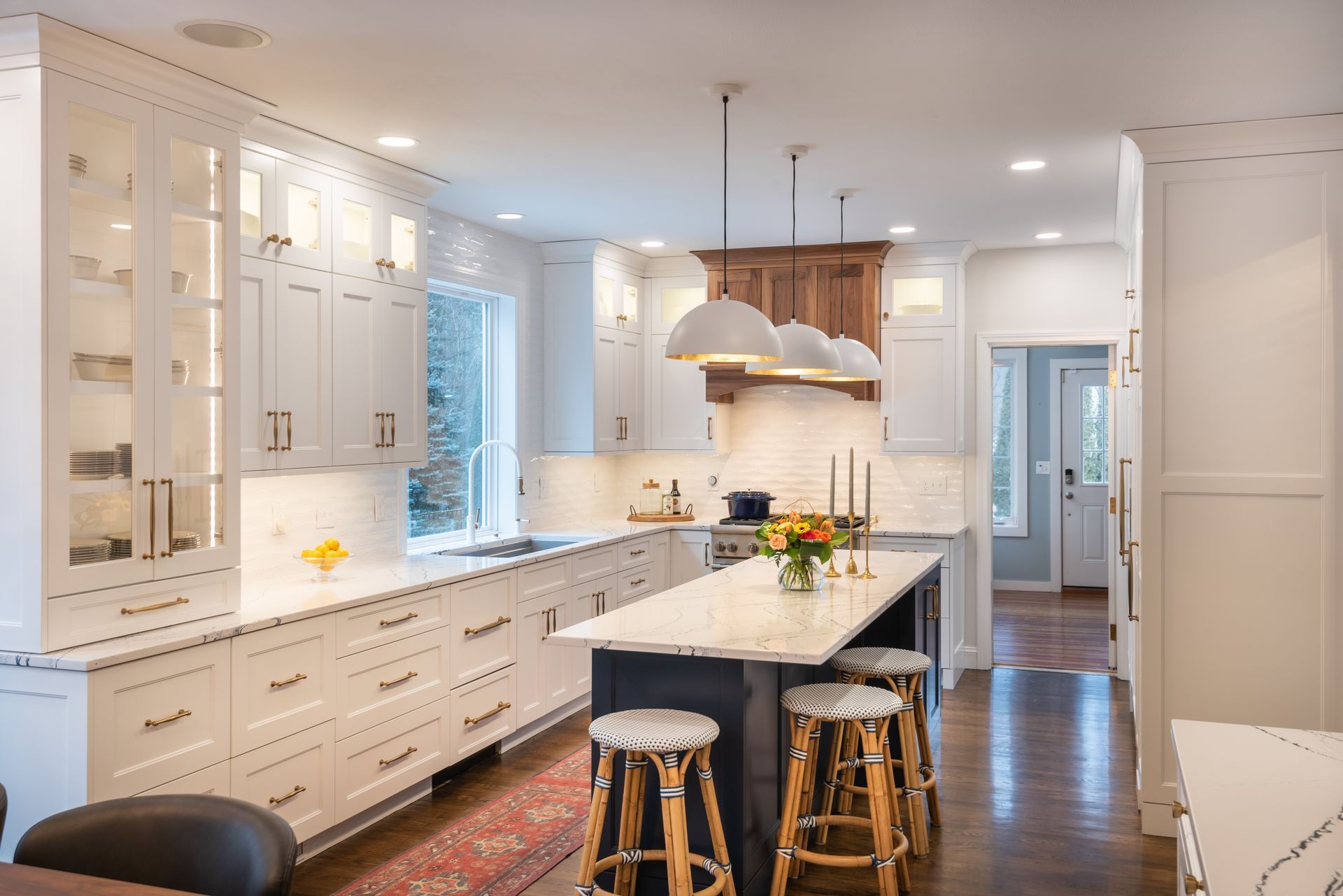 Bright modern kitchen with white cabinets, island, stools, and wood floor