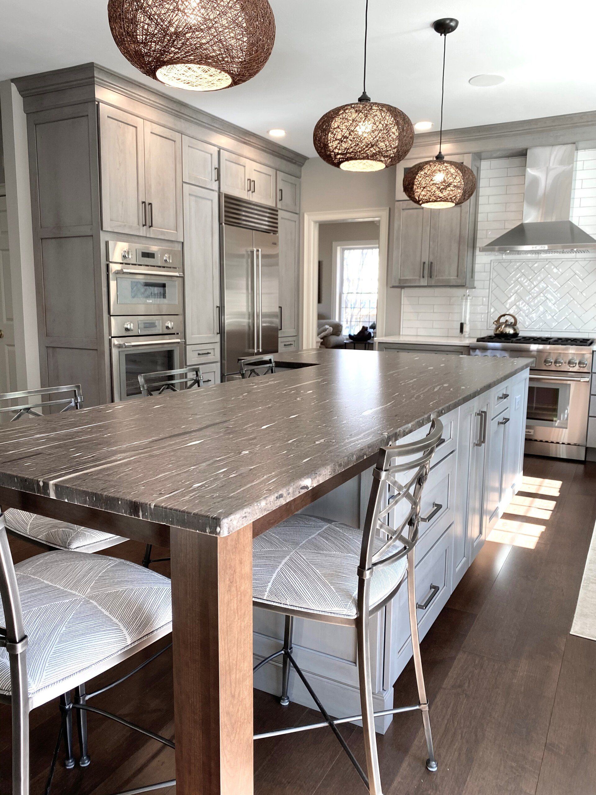 Modern kitchen with stainless steel appliances, dark wood cabinets, and a granite island with pendant lights.