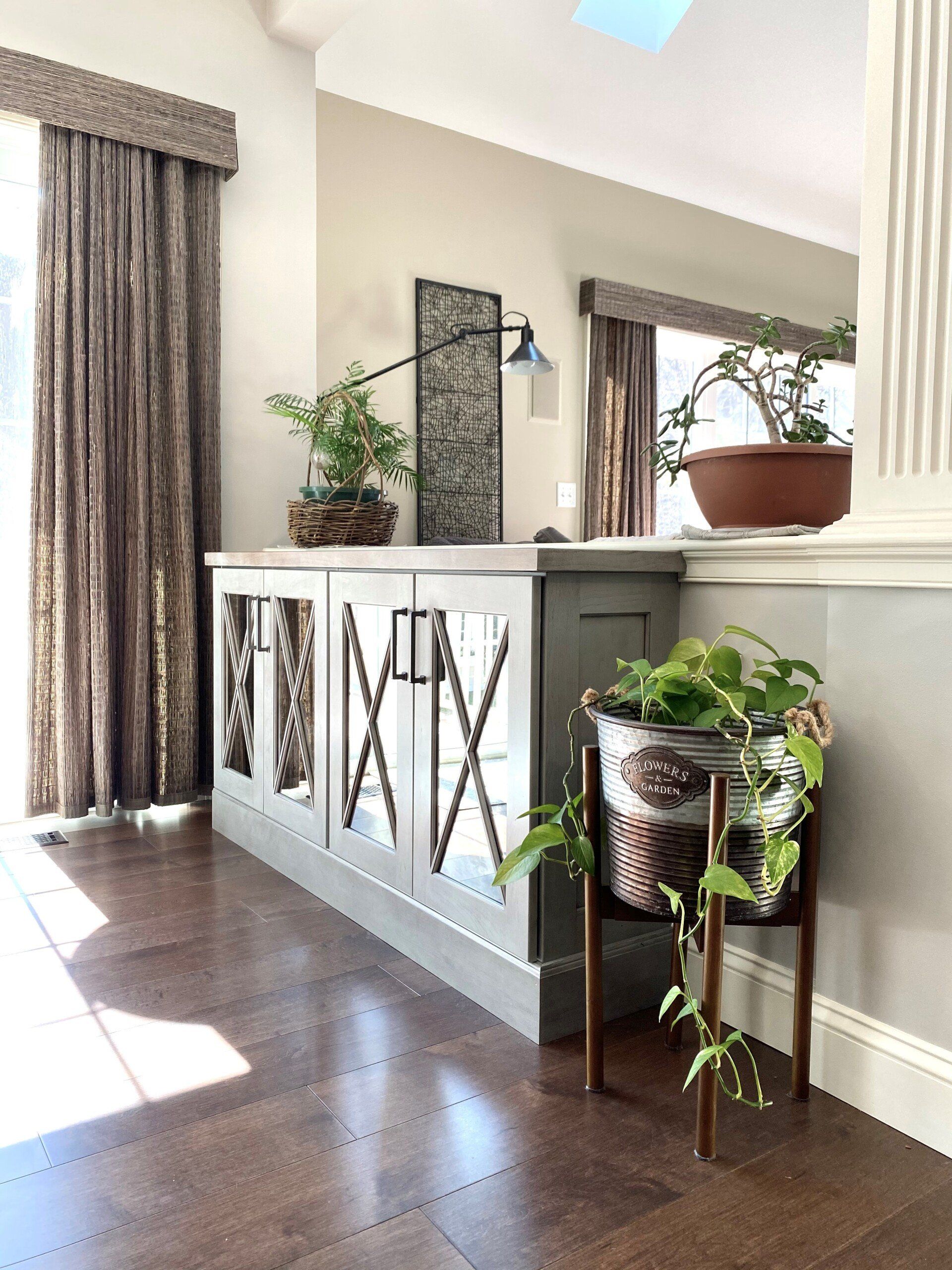 Bright living room with white console table, potted plants, and brown curtains on hardwood floors