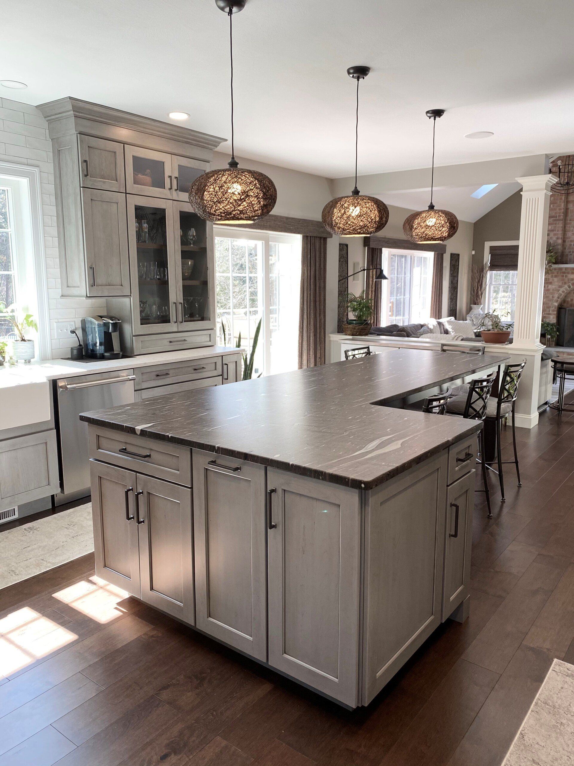 Bright modern kitchen with large island, pendant lights, white cabinets, and hardwood floors