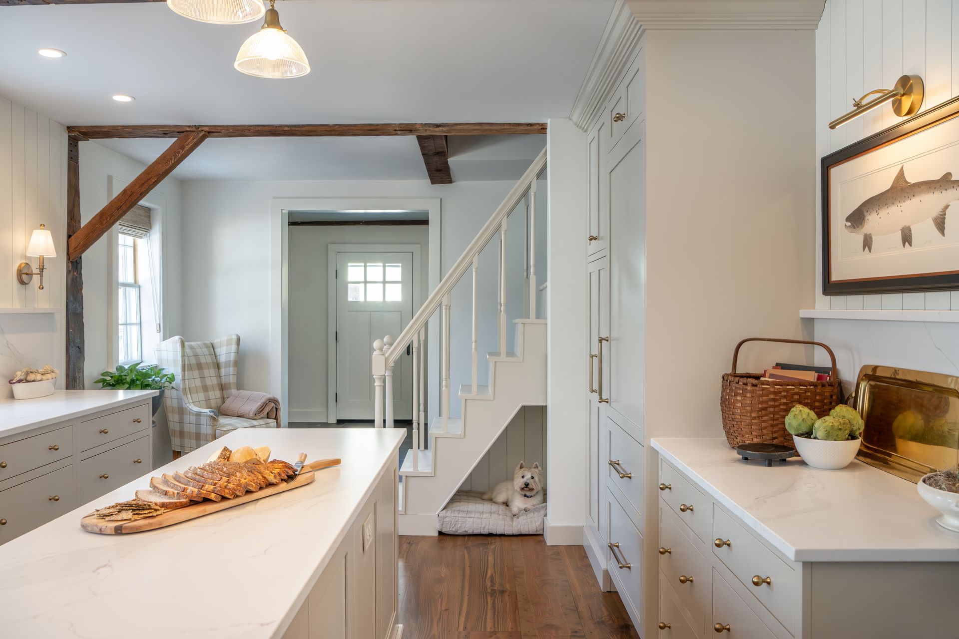Bright white kitchen with island, staircase, and open hallway in a modern farmhouse interior