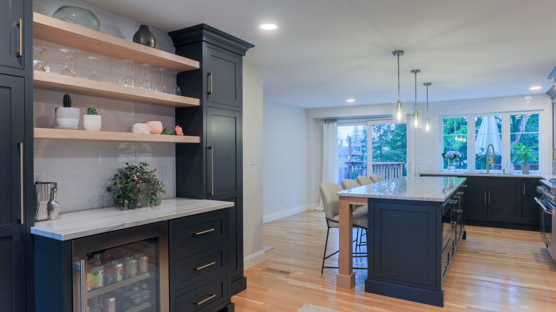 Modern kitchen with dark cabinets, open shelves, island seating, and bright windows overlooking a dining area