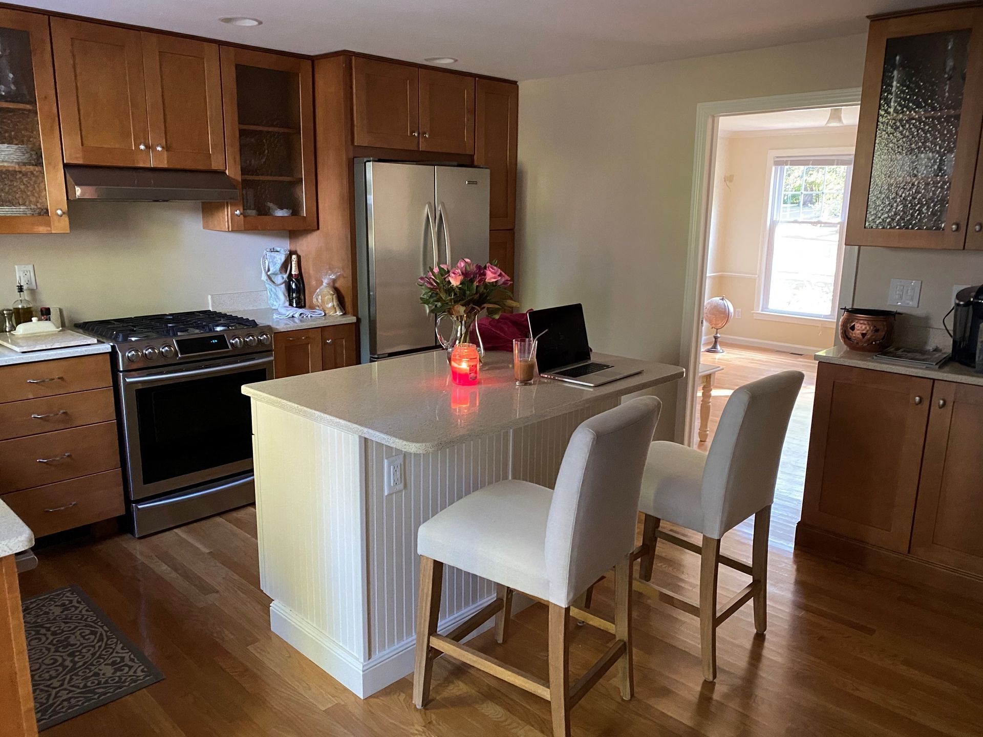 Bright kitchen with wood cabinets, stainless steel appliances, and a white island with two chairs