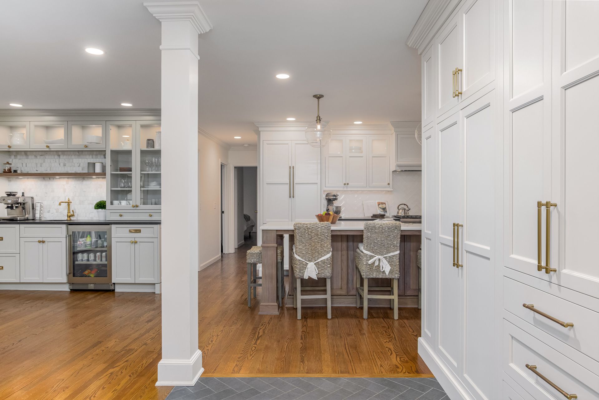 Bright white kitchen and dining area with wood floors, island seating, and built-in cabinetry
