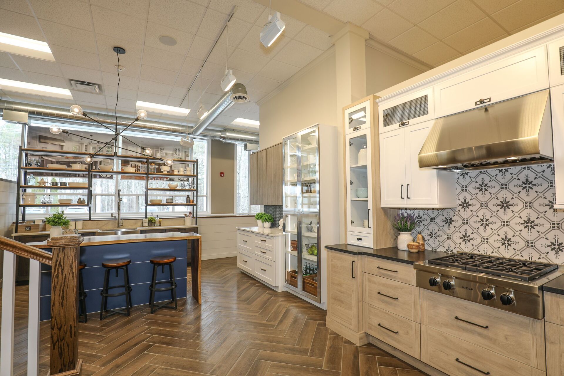 Modern kitchen with wood cabinets, herringbone floor, blue island, and tiled stove backsplash