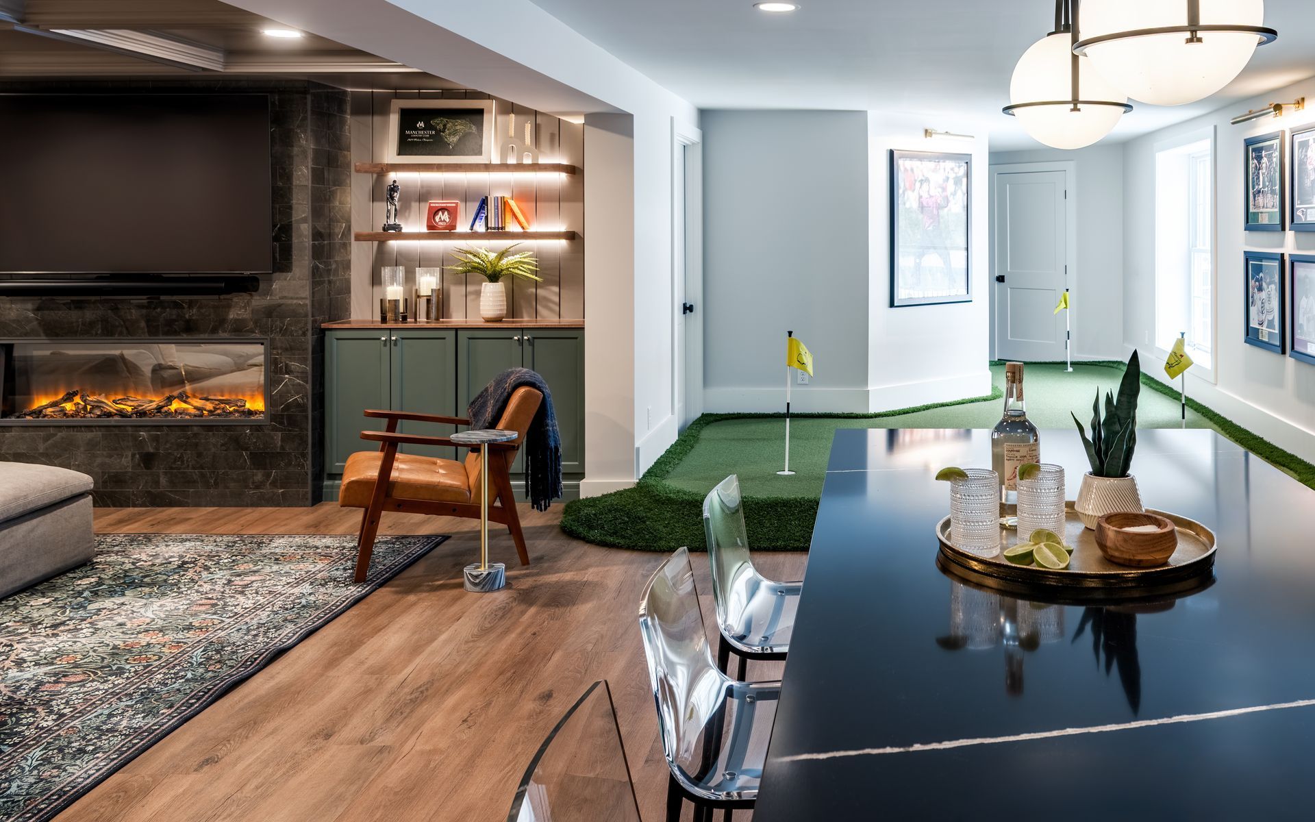 Modern living room with fireplace, black dining table, green seating, and wood flooring