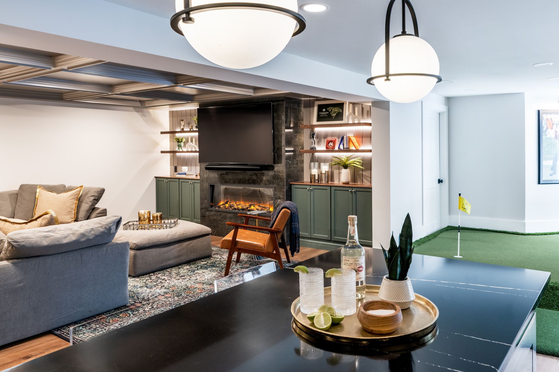 Modern living room with sectional sofa, fireplace, TV, and dining area under pendant lights