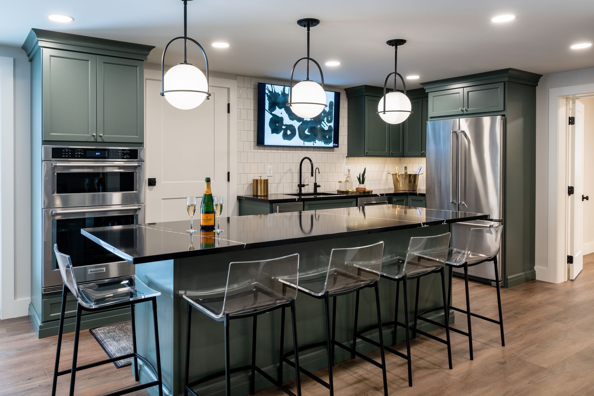 Modern kitchen with gray cabinets, black island, pendant lights, and stainless steel appliances