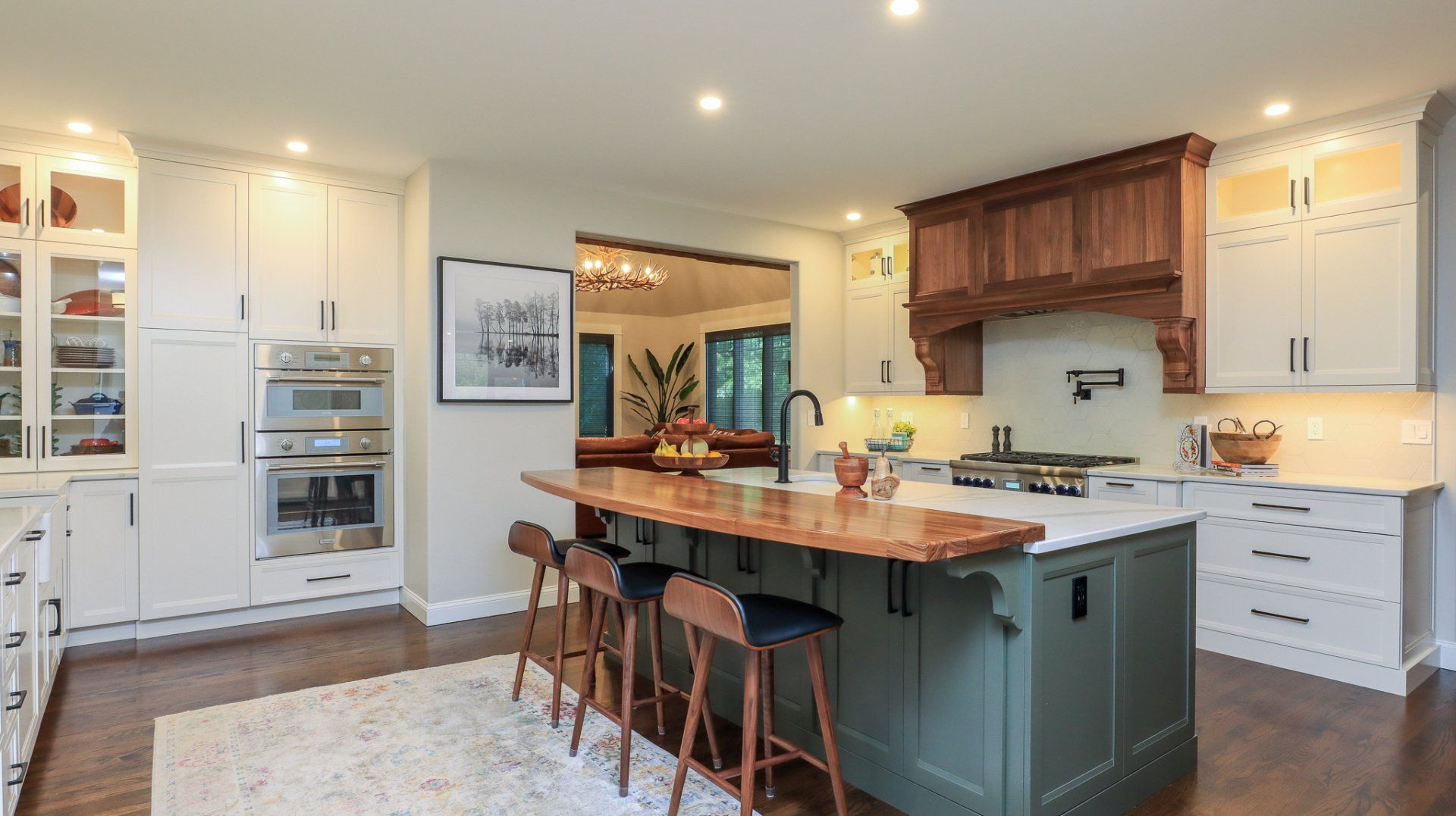 Bright modern kitchen with white cabinets, wood island, and bar stools under warm lighting