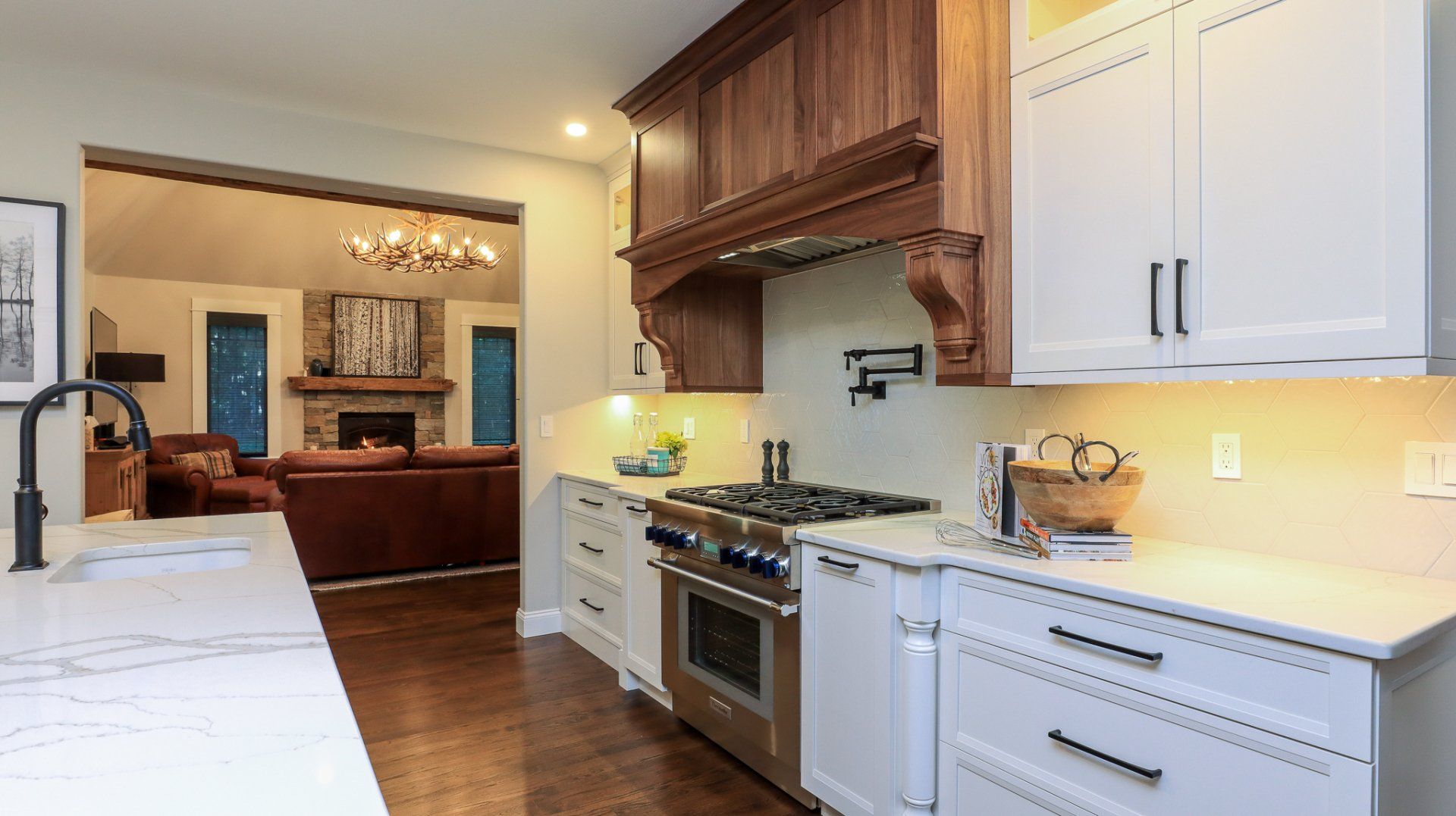Bright modern kitchen with white cabinets, farmhouse sink, and wood hood beside an open dining room.