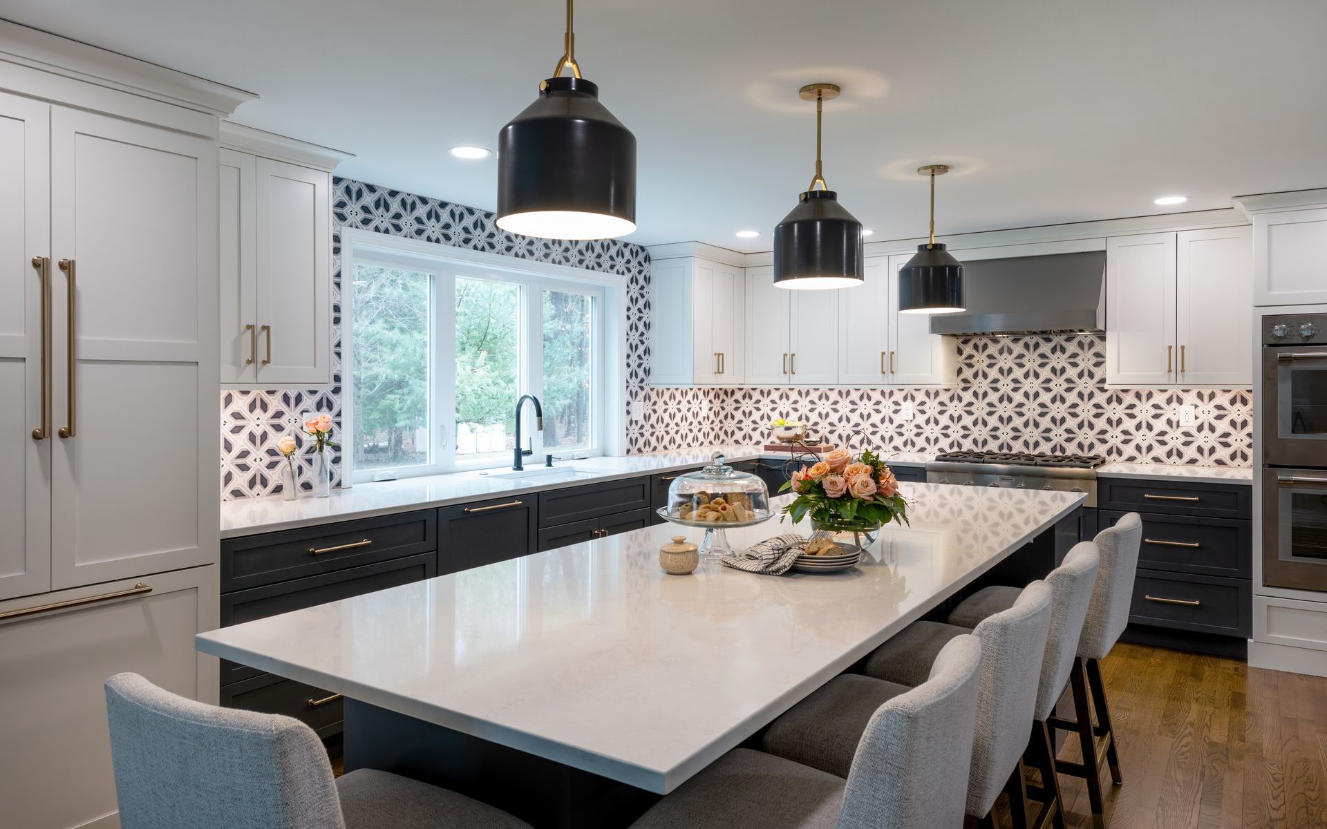 Modern white kitchen with black island, pendant lights, and large window over the sink