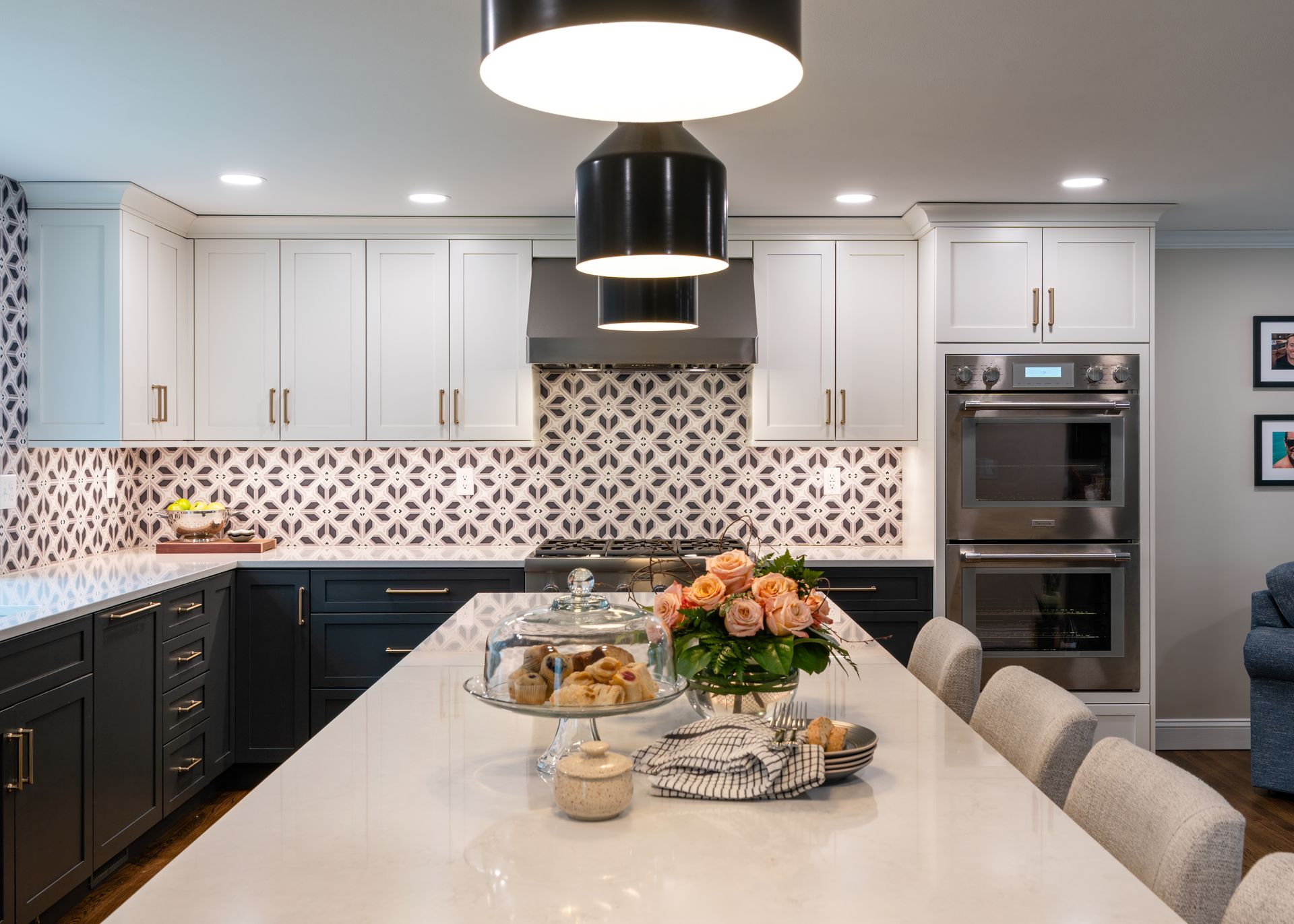 Modern kitchen with white and dark cabinets, floral backsplash, island centerpiece, and built-in ovens