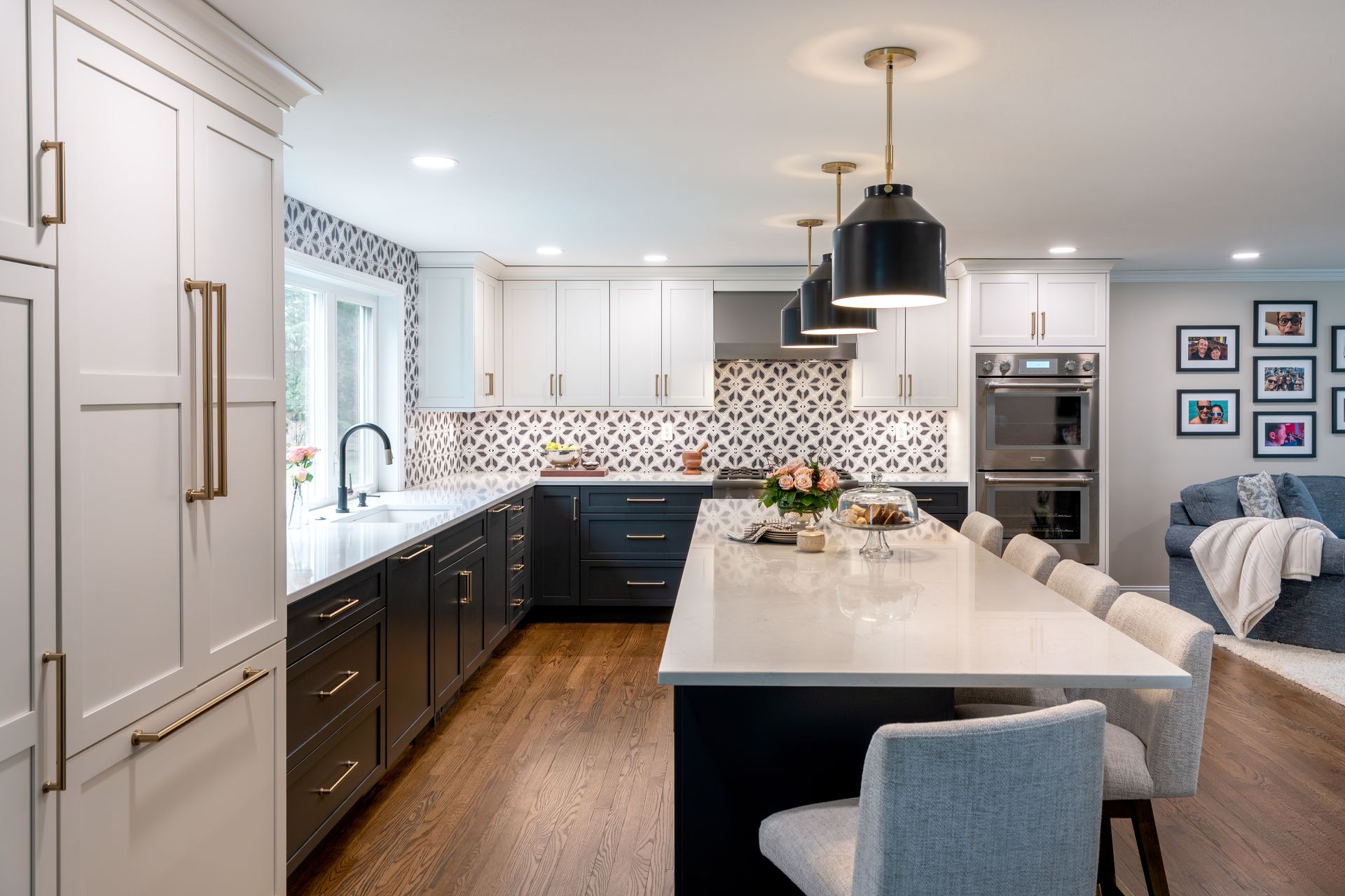 Modern kitchen with white island, dark cabinets, stainless appliances, and pendant lights