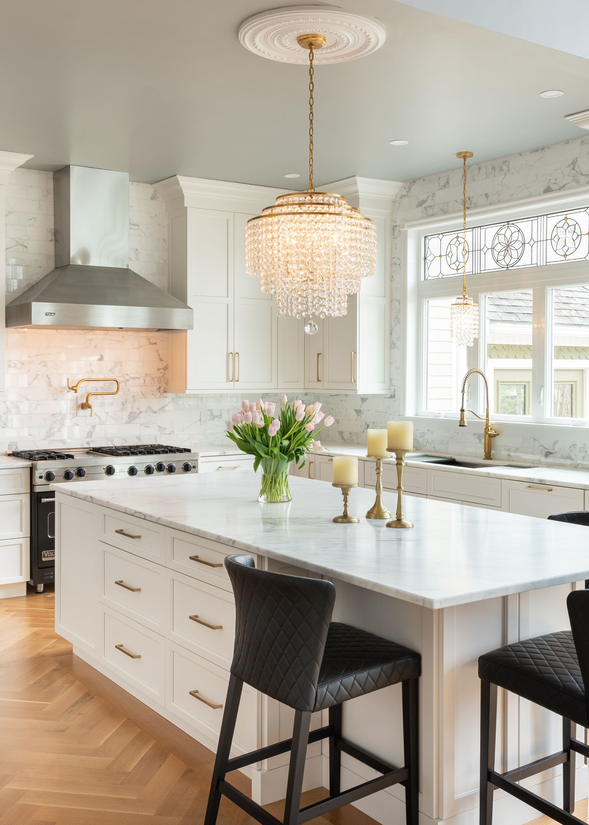 Bright modern kitchen with white island, pendant light, and two dark bar stools by a window