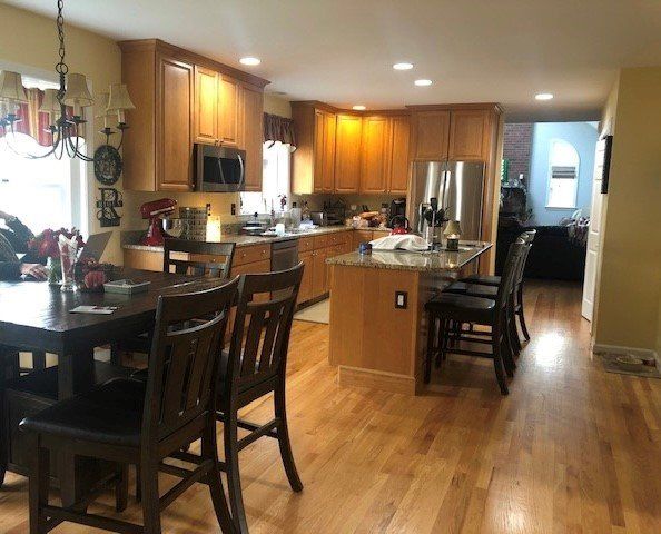 Spacious kitchen with wooden cabinets, island seating, stainless steel appliances, and hardwood floors