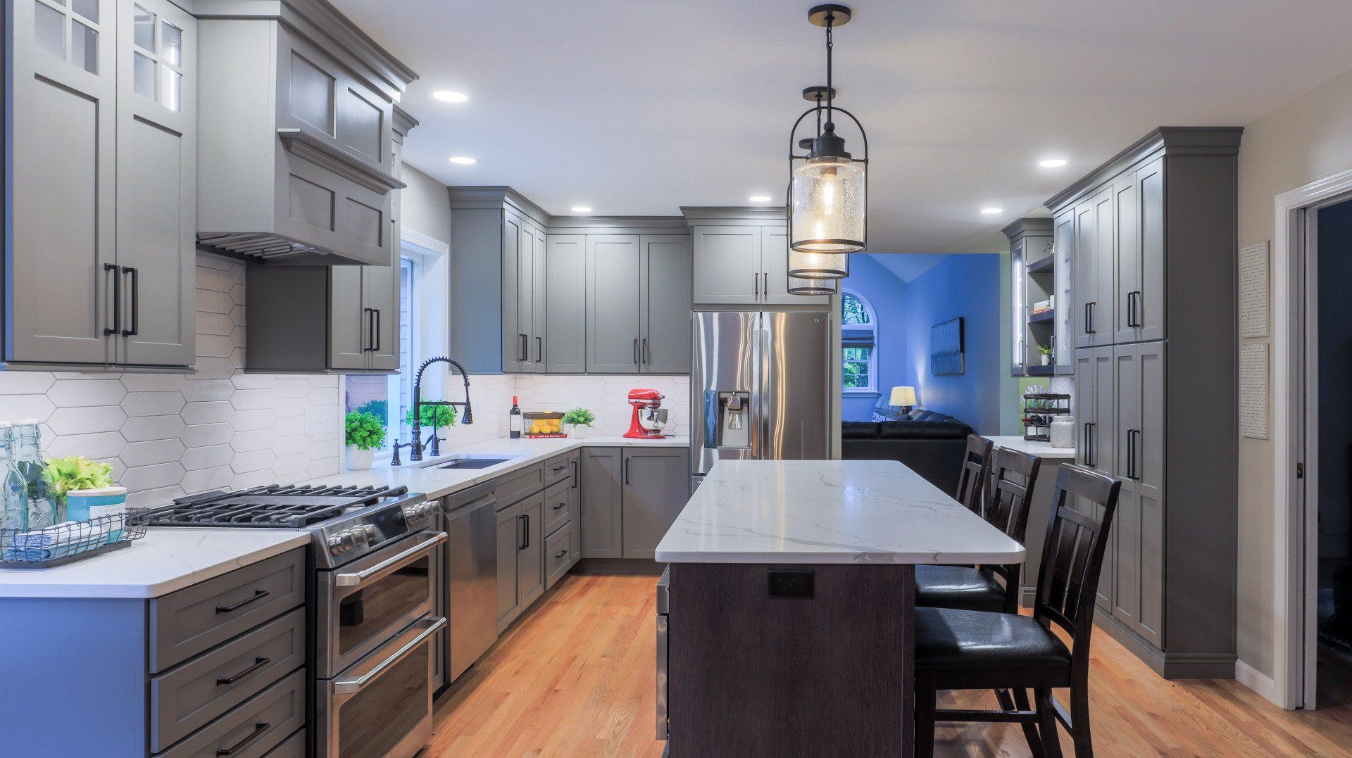 Modern gray kitchen with island, stainless appliances, pendant lights, and wood floors