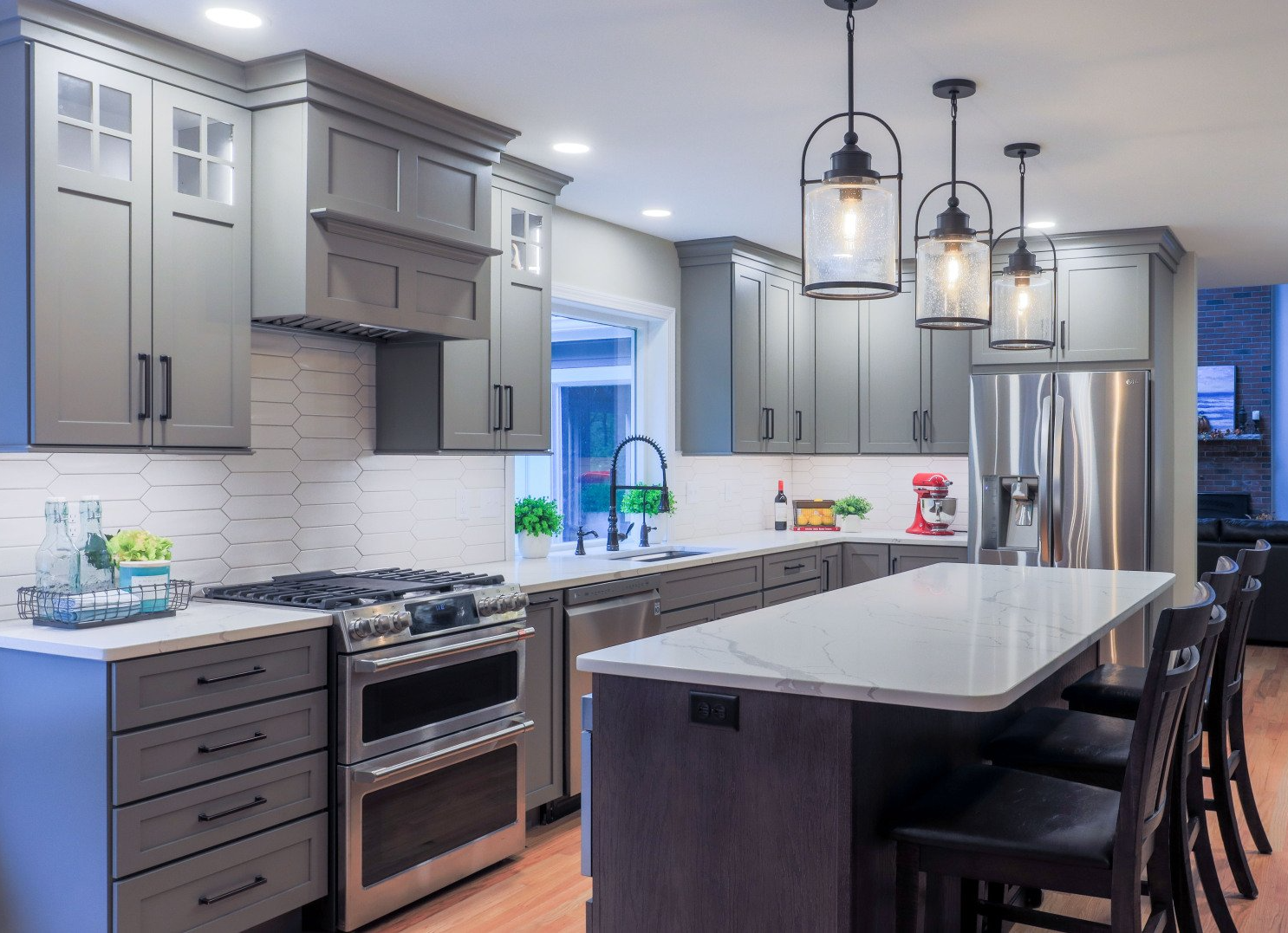 Modern kitchen with gray cabinets, large island, pendant lights, and bar stools