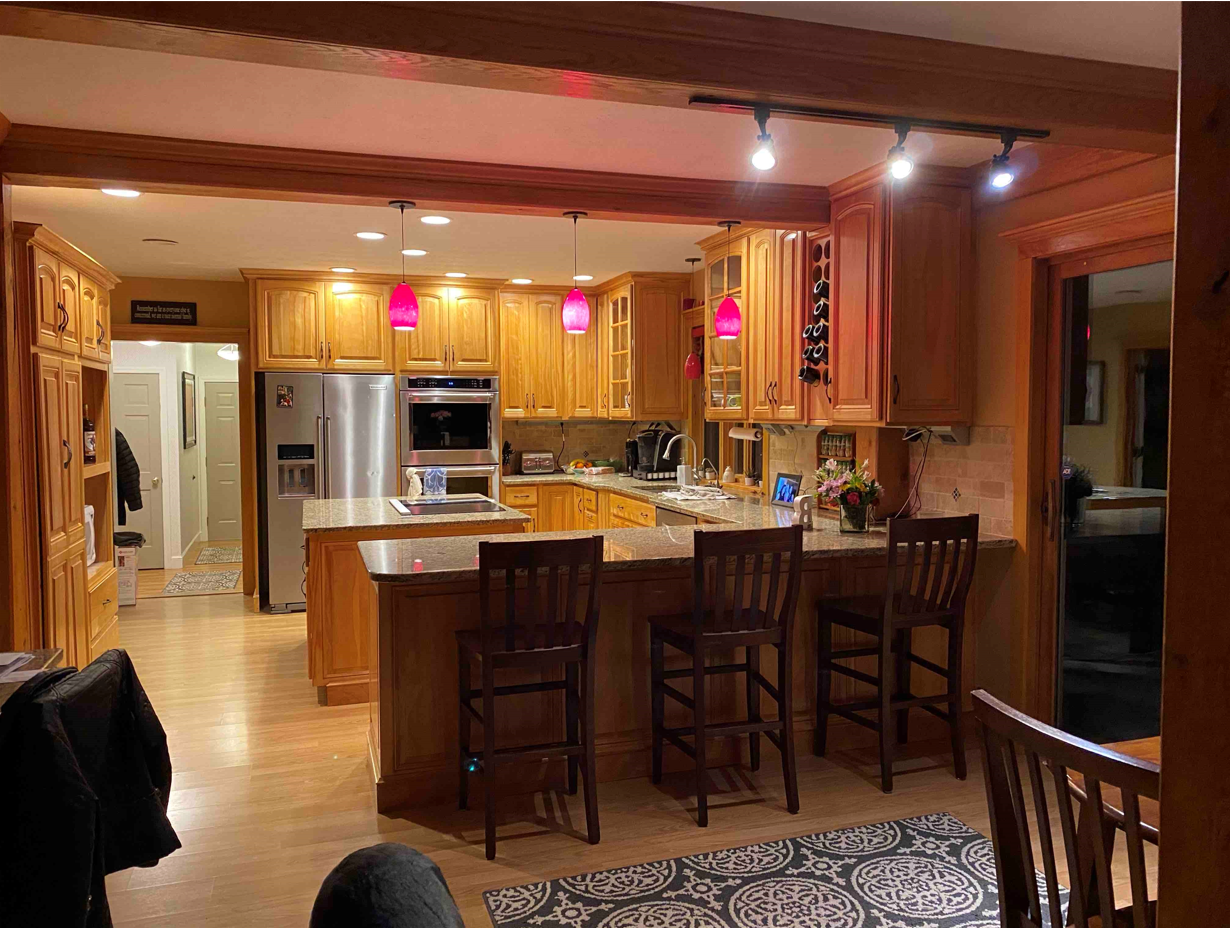 Warm kitchen with wooden cabinets, stainless appliances, and a large island with bar stools in a cozy home interior