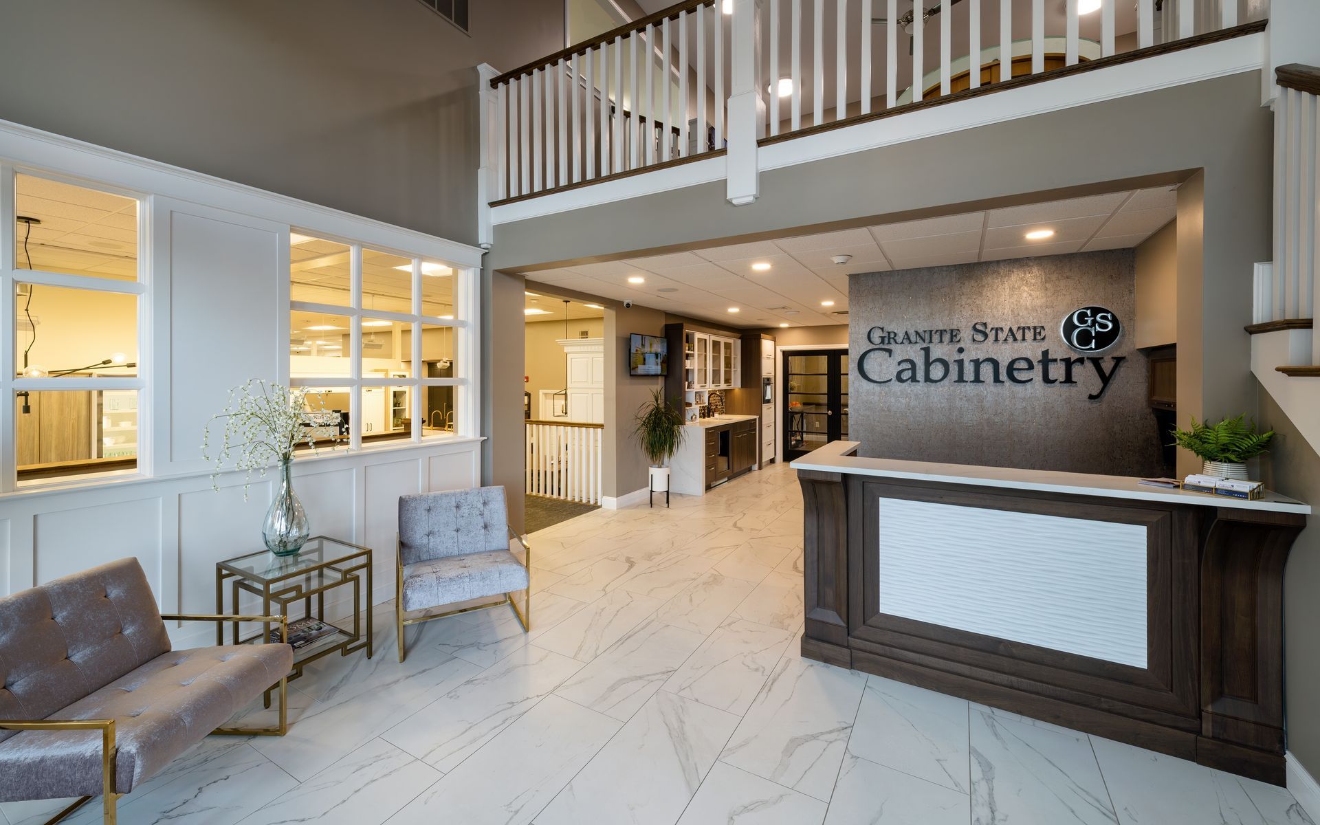 Bright lobby with marble floor, seating area, and dark reception desk labeled “Cabinetry”