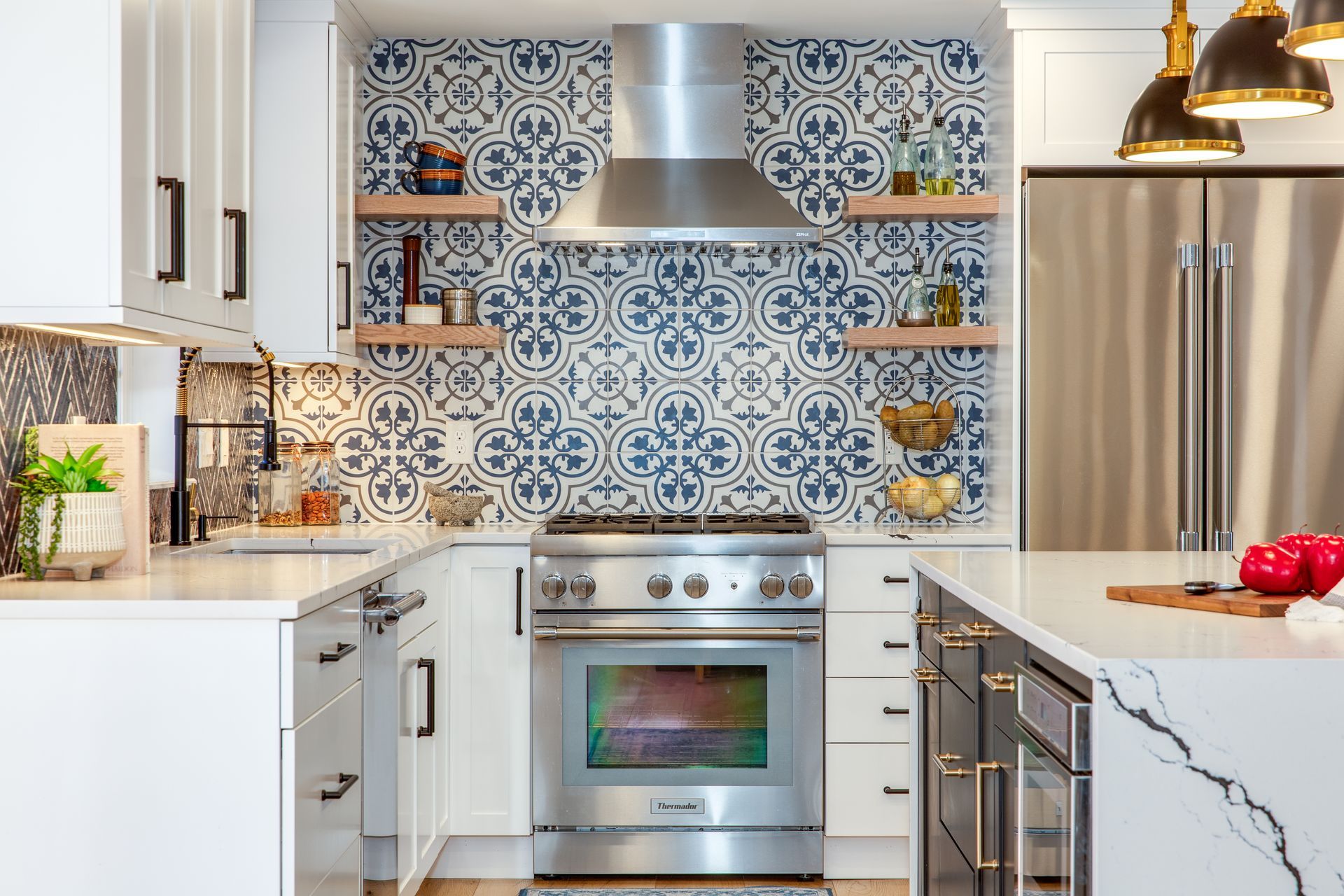 Modern kitchen with blue patterned backsplash, stainless steel appliances, and white marble countertops