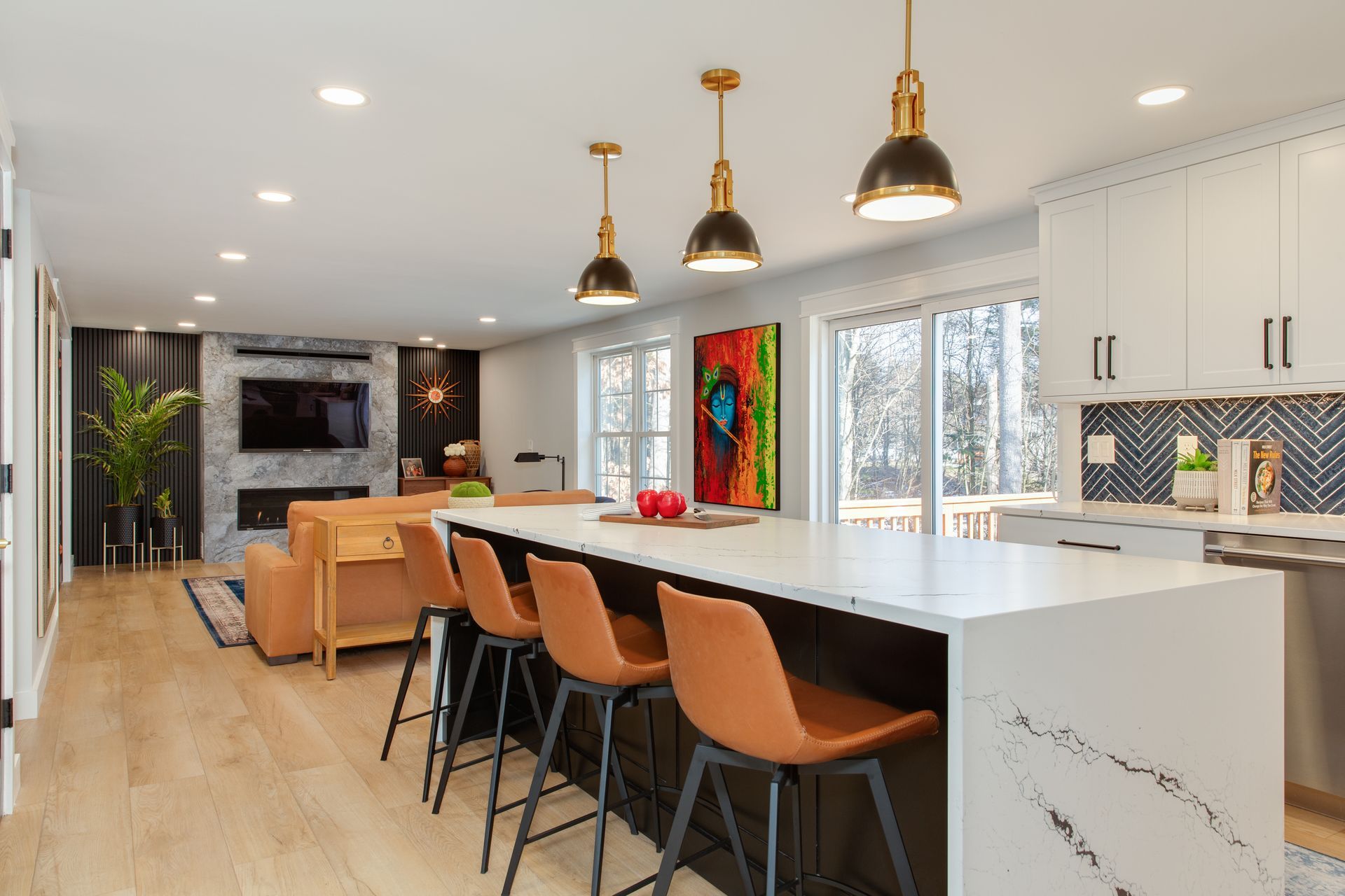 Modern open kitchen with white island, tan bar stools, pendant lights, and living area beyond