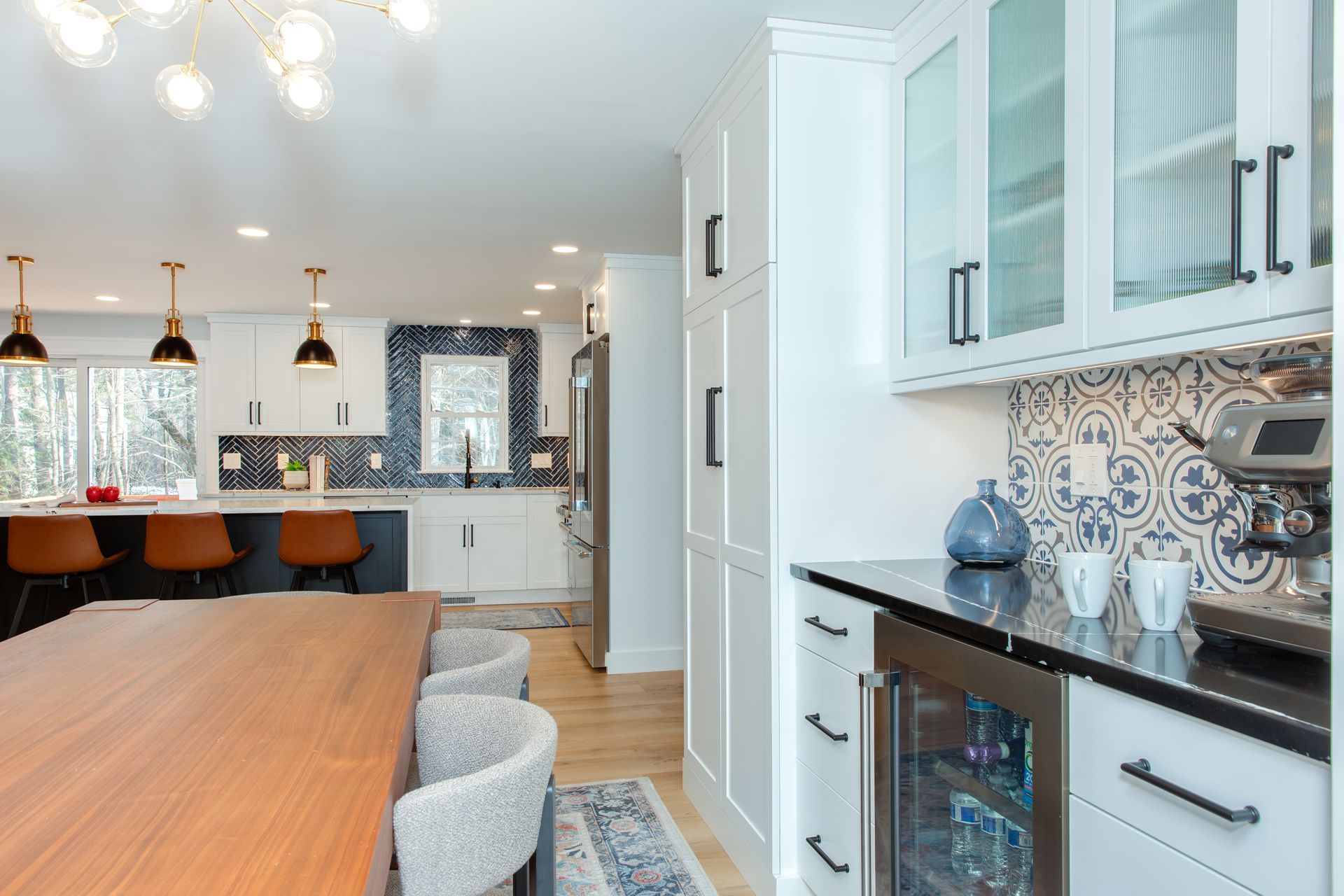 Bright modern kitchen and dining area with white cabinets, black countertops, and wood table