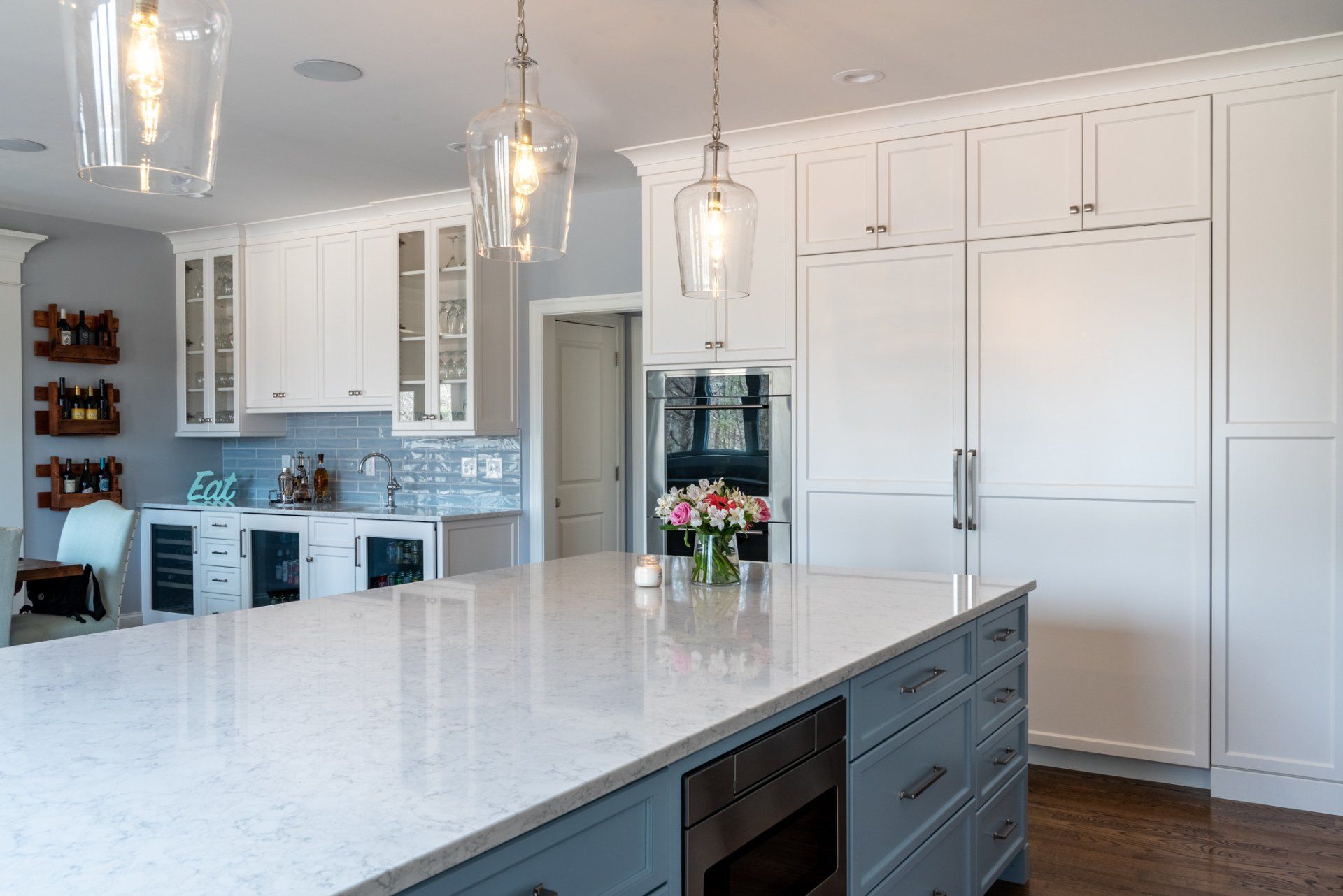 Bright white modern kitchen with large island, pendant lights, and built-in cabinets