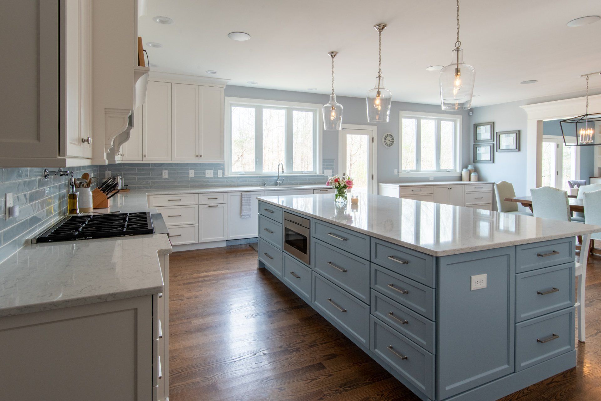 Bright modern kitchen with blue island, white cabinets, and hardwood floors