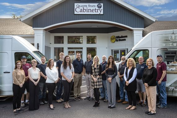 Group of people standing outside a cabinet shop between two white vans