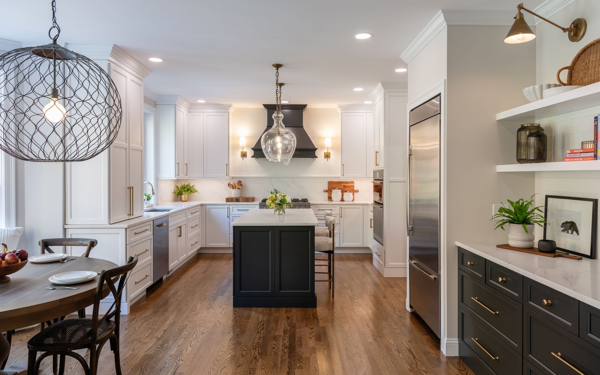 Bright modern kitchen with white cabinets, dark island, wood floor, and pendant lights
