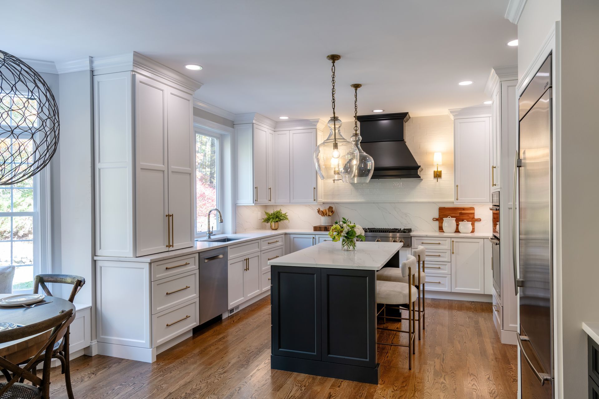 Bright modern kitchen with white cabinets, black island, and hardwood floors