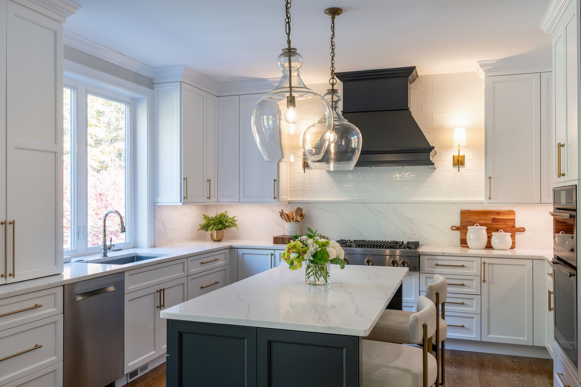 Bright modern kitchen with white cabinets, marble island, pendant lights, and flowers on the counter