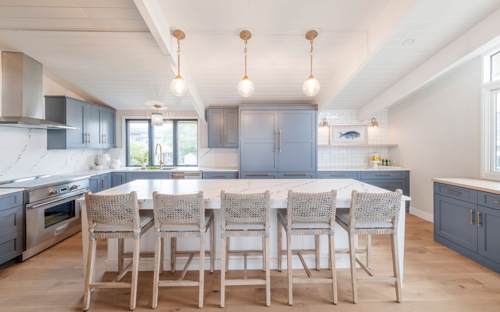 Bright modern kitchen with white island, barstools, gray cabinets, and pendant lights
