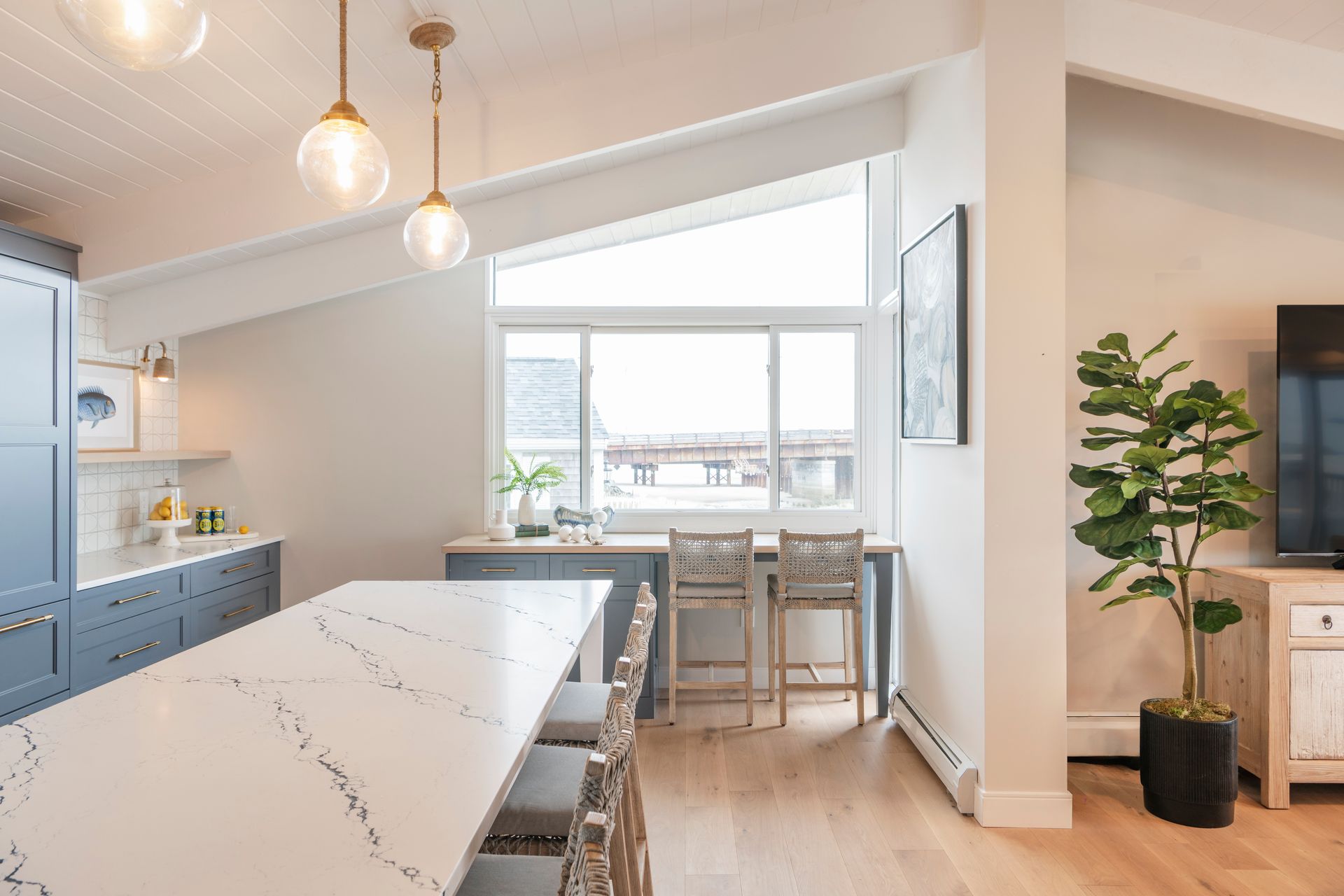 Bright modern kitchen and dining area with white island, bar stools, and large window seating.