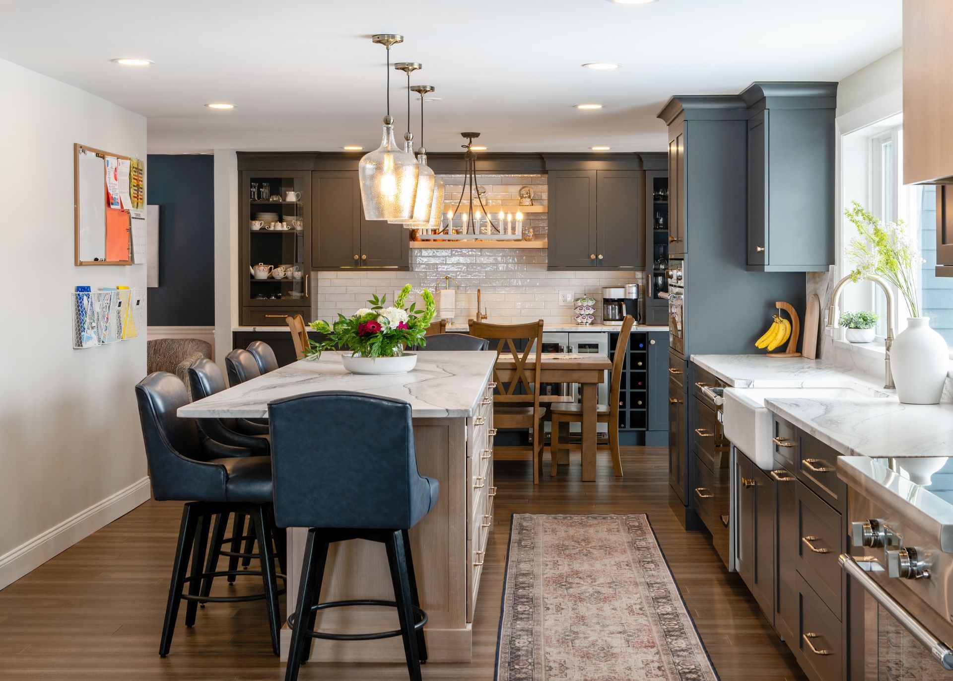 Modern kitchen with island seating, pendant lights, and white countertops by a sunlit window