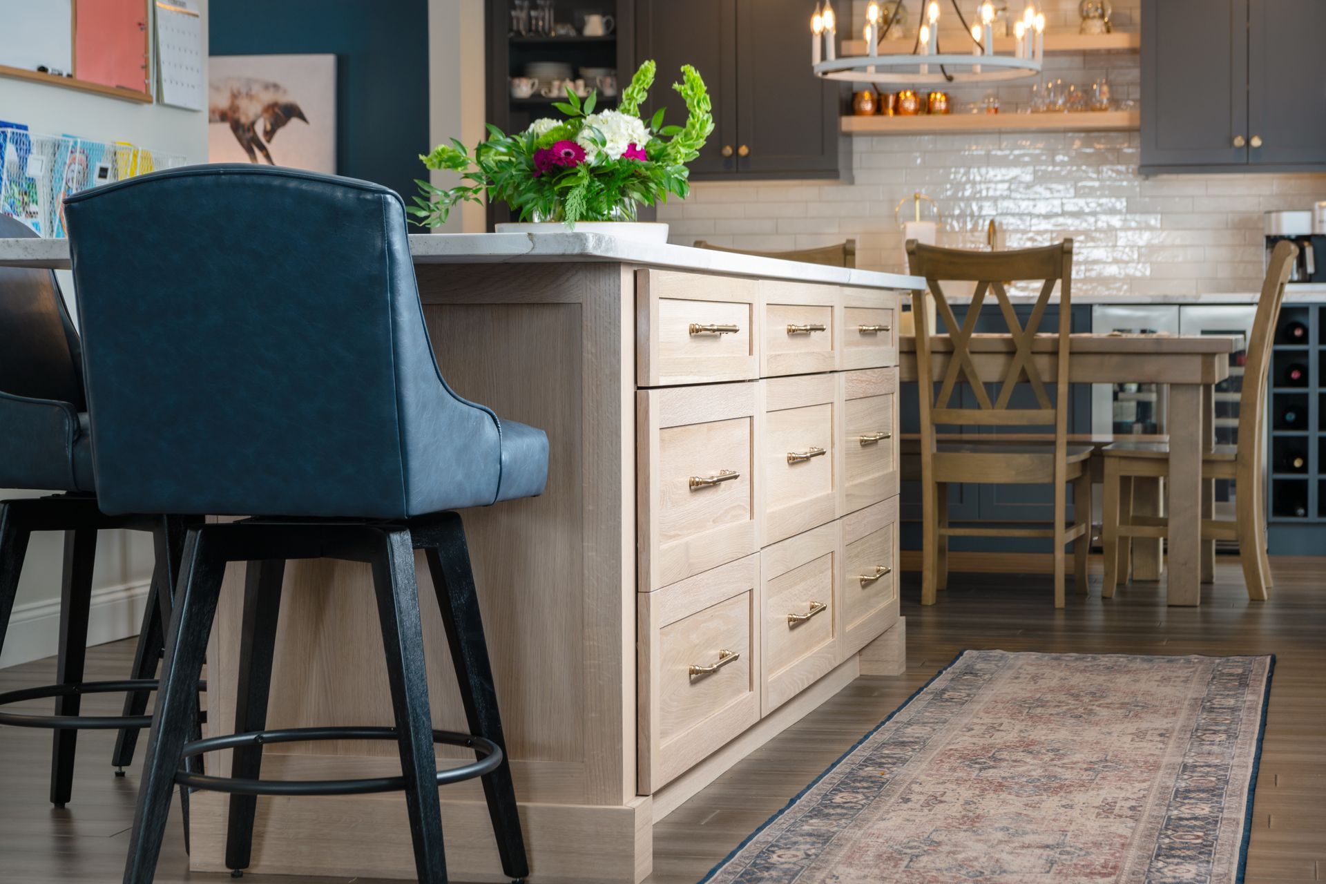 Modern kitchen with blue bar stools, white island, dining table, and rug