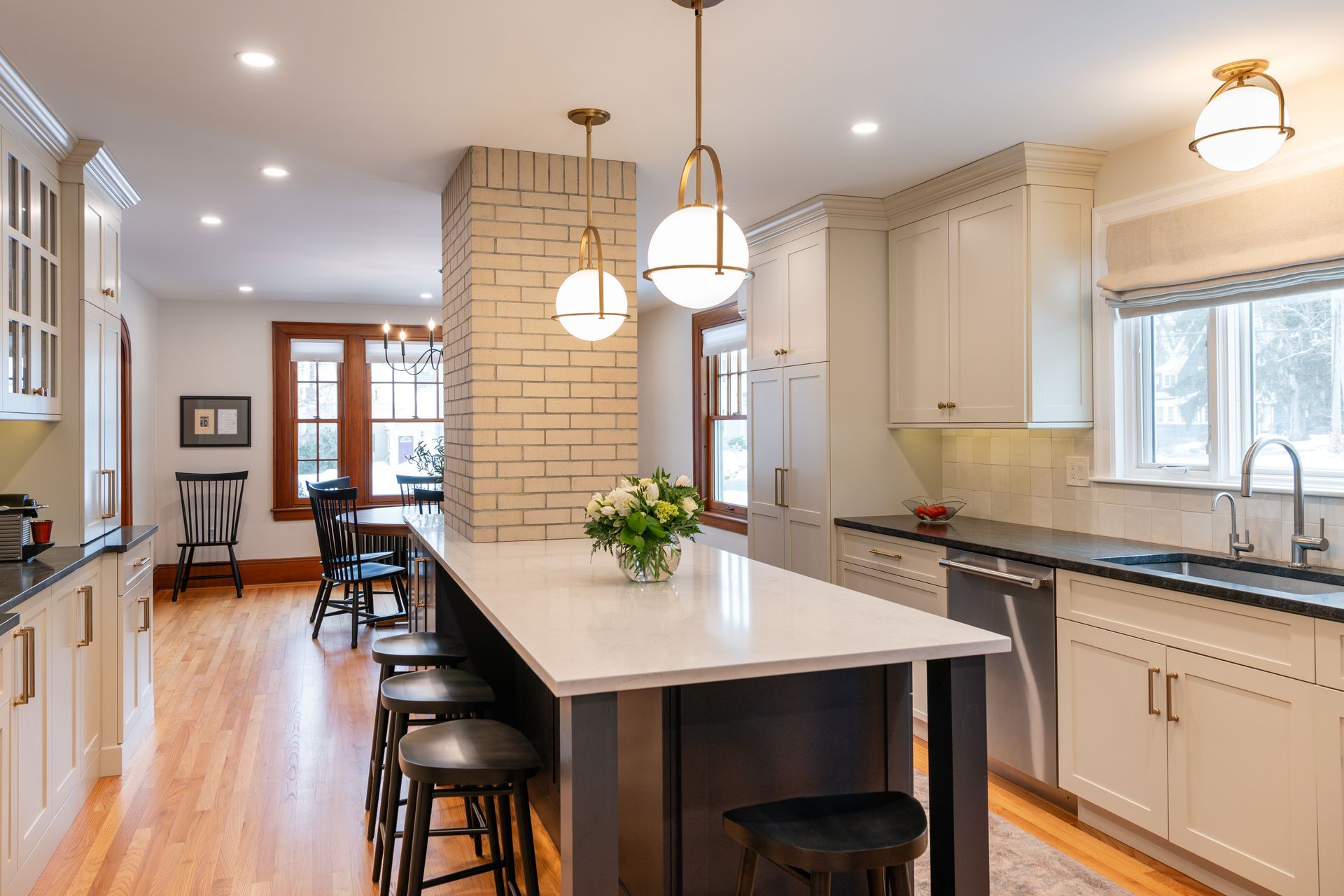 Bright modern kitchen with island, pendant lights, white cabinets, and hardwood floors