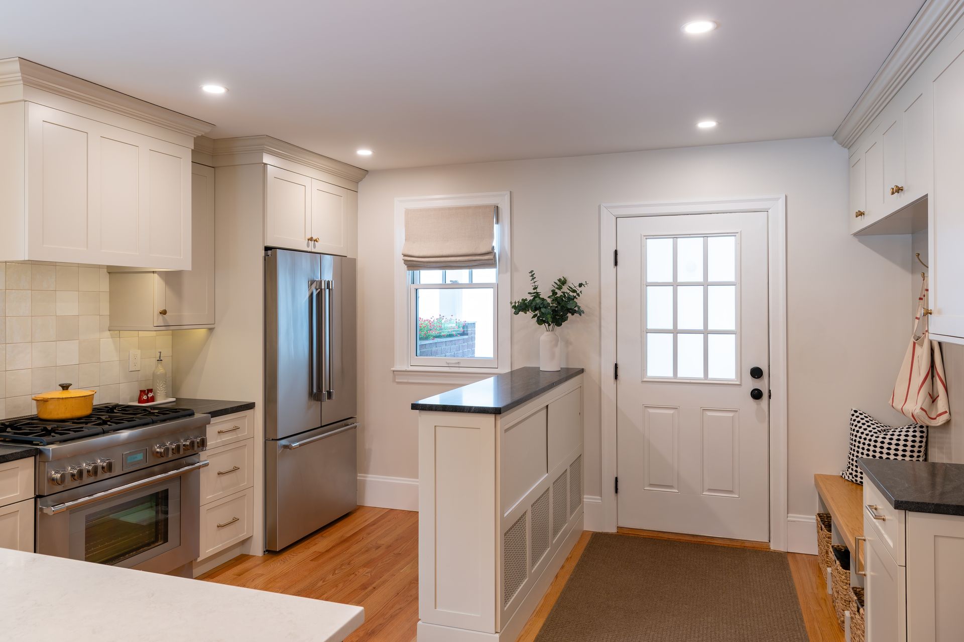 Bright modern kitchen with white cabinets, stainless appliances, island, and a door to the outside