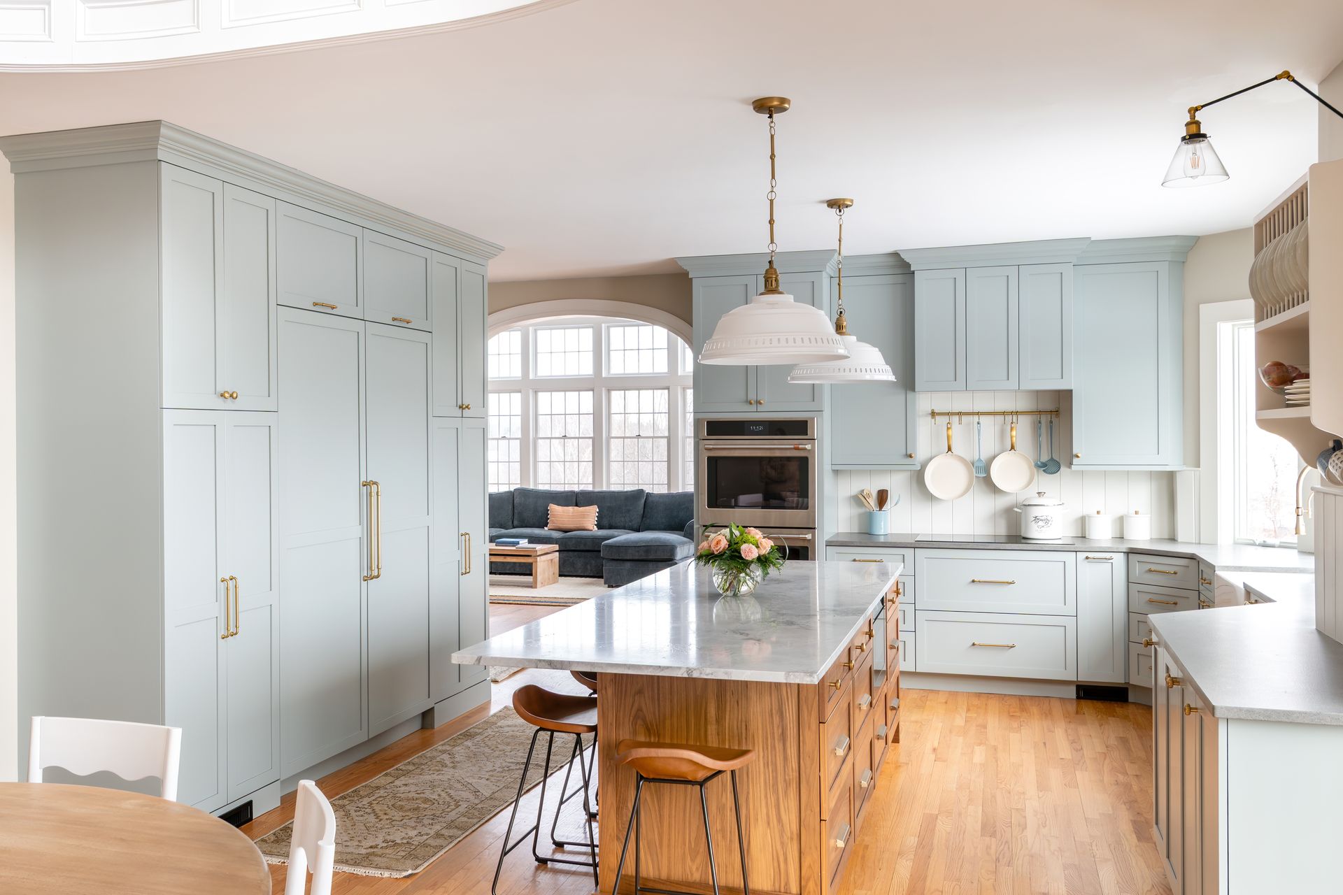 Bright modern kitchen with gray cabinets, wooden island, pendant lights, and a dining nook by a window